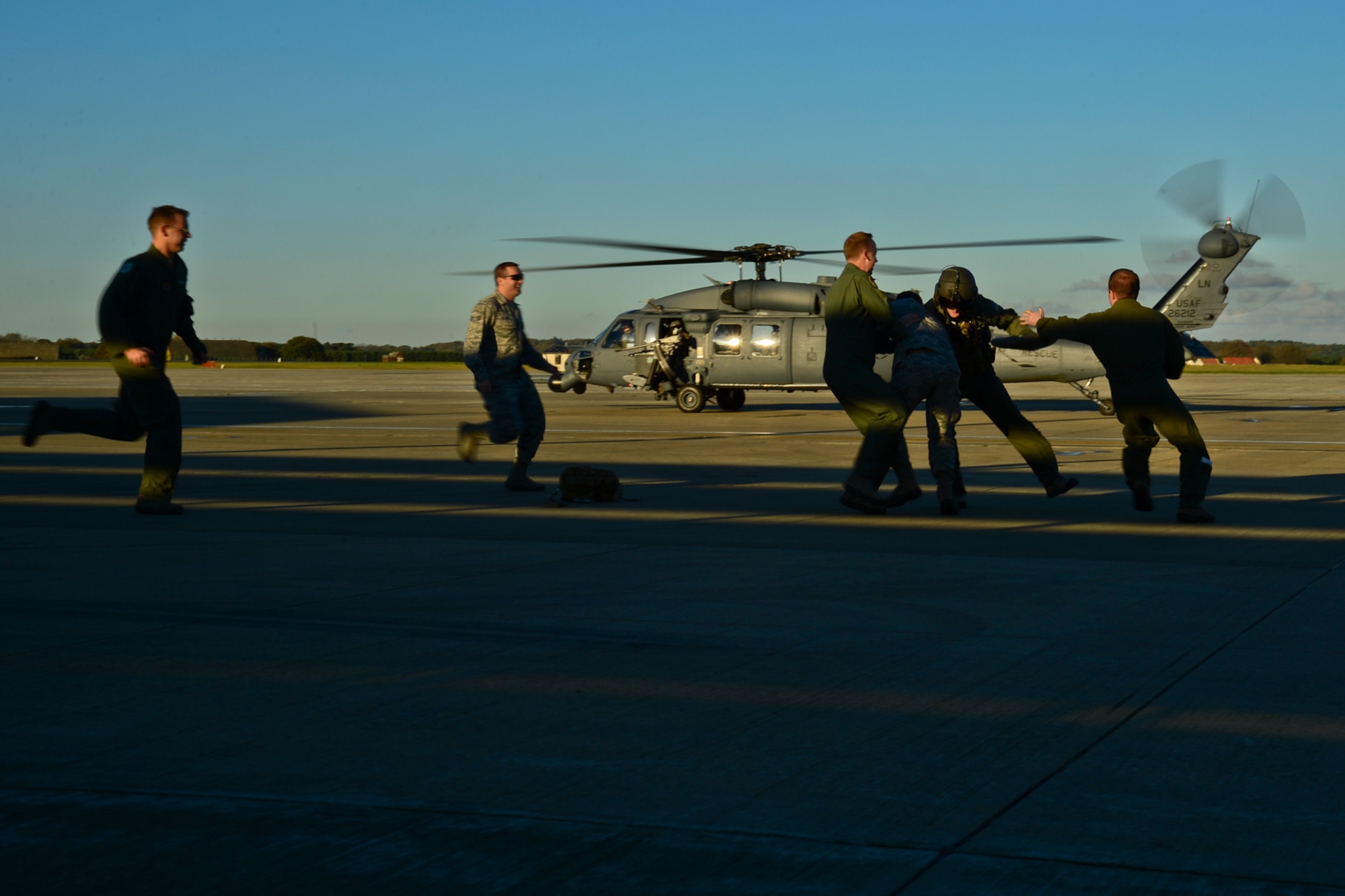 Airmen from the 56th Rescue Squadron tackle Capt. Robert Smith after his fini-flight Nov. 4, 2014, at Royal Air Force Lakenheath, England. It is a tradition to ‘capture’ a pilot after his final flight and paint his feet green to stamp on a ceiling tile.  Smith is the 56th RQS executive officer. (U.S. Air Force photo/Airman 1st Class Erin R. Babis)