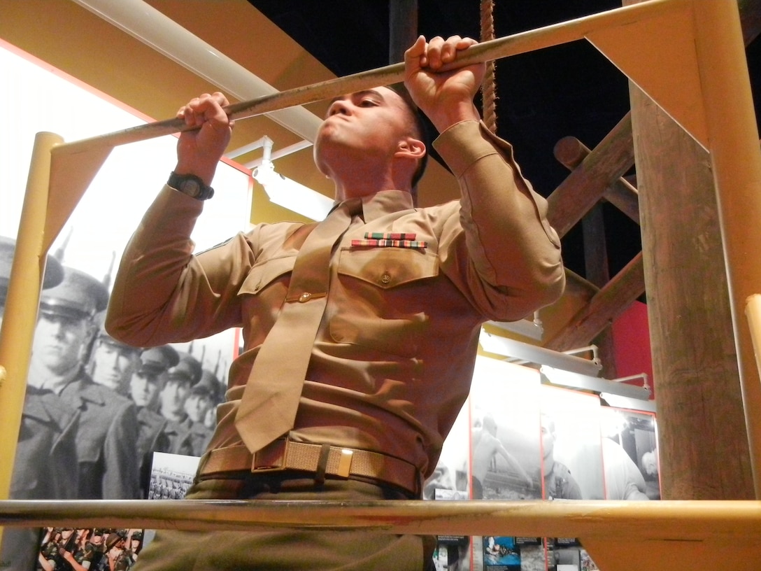 Sgt. Michael Hough, intelligence analyst, Marine Corps Intelligence Activity, demonstrates to teenagers how to properly do pull-ups during Saturday’s Leadership Mentor Workshop at the National Museum of the Marine Corps.