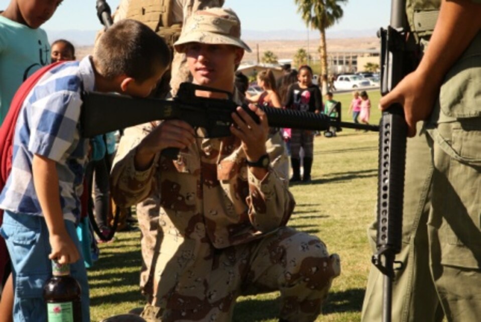 Sgt. Phillip Mitchell, motor transportation operator, Headquarters Battalion, lets a student from the Morongo Unified School District look through the sights of an M16 A4 service rifle after the uniform pageant and cake-cutting ceremony at Lance Cpl. Torrey L. Gray Field, Nov. 6. At the end of the ceremony, elementary and middle-school students from schools participating were able to talk to role-players directly. (Official Marine Corps photo by Cpl. Charles Santamaria/ Released)