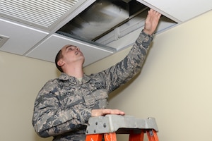 U.S. Air Force Staff Sgt. Franklin Sallis, 633rd Civil Engineering Squadron heating and ventilation craftsman, removes a ceiling panel from inside a dormitory kitchen at Langley Air Force Base, Va., Nov. 20, 2014. Sallis was preparing to reprogram the ventilation system’s computer. (U.S. Air Force photo by Airman 1st Class Devin Scott Michaels/Released)