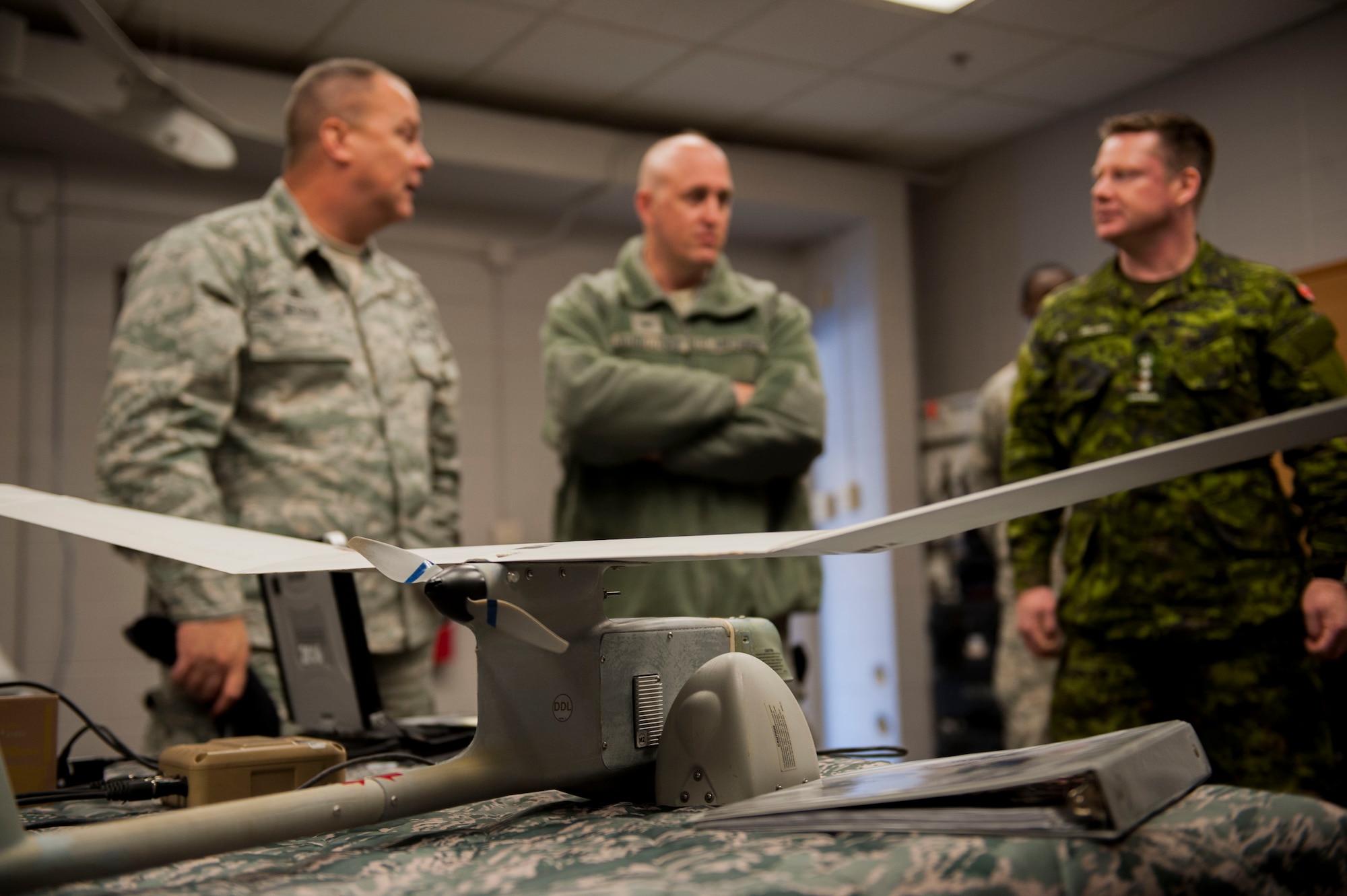 U.S. Air Force Col. Mike Ross, left, 820th Base Defense Group commander, speaks with Col. Erik Rundquist, middle, Air Combat Command chief of security forces, and Canadian forces Col. Robert Delaney, Department of National Defence provost marshal, during an 820th BDG tour Nov. 19, 2014, at Moody Air Force Base, Ga. Ross discussed the capabilities of the RQ-11B Raven small unmanned aircraft system and its use for base defense. (U.S. Air Force photo by Airman 1st Class Dillian Bamman/Released)