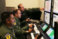 Front to back: Staff Sgt. Jesus, 558th Flying Training Squadron sensor operator instructor, and 2nd Lt. James, 558th FTS Remotely Piloted Aircraft pilot trainee, are instructed by Capt. Gary, 558th FTS instructor pilot on weapons employment procedures. (U.S. Air Force photo by Airman 1st Class Alexandria Slade/Photo illustration by Maggie Armstrong) 