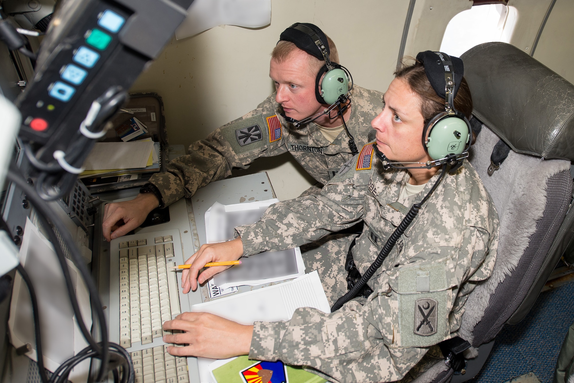 U.S Army Capt. Christopher Thornton, left, a deputy mission crew commander, 138th Military Intelligence Company, provides Capt. Michelle Roberts, deputy intelligence officer from the 118th Infantry Battalion, South Carolina National Guard, hands-on training at his operator work station aboard the E-8C Joint STARS aircraft during exercise Operation Carolina Thunder, Robins Air Force Base, Ga., Nov. 15, 2014.  During the exercise, Airmen and Soldiers from the 116th Air Control Wing and the 138th Military Intelligence Company provided targeting data and intelligence to F-16 Fighting Falcons, AH-64D Apache Attack Helicopters and ground forces using the one-of-a-kind battle management command and control, intelligence, surveillance and reconnaissance capabilities of the E-8C Joint STARS. The exercise was a multi-state, multi-component, collective training exercise conducted during the South Carolina drill weekend. It involved more than 650 participants from South Carolina, North Carolina, Georgia and Tennessee National Guard units.  (Portion of photo blurred for security purposes) (U.S. Air National Guard photo by Tech. Sgt. Regina Young/released)
