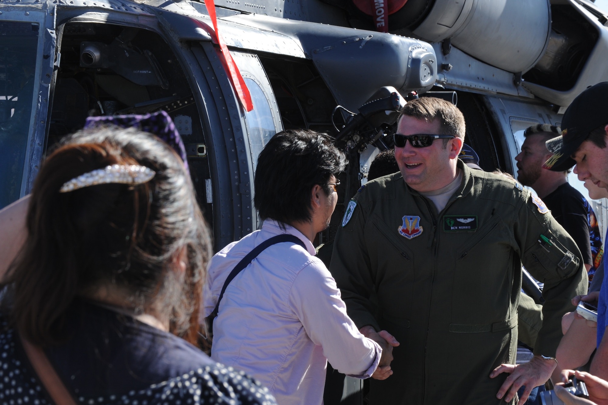 Capt. Ben Norris, 66th Rescue Squadron aircraft commander, shakes hands with a member of the public during the Nellis Open House at Nellis Air Force Base, Nev., Nov. 8, 2014. Norris, along with other members of the 66th RQS, shared their knowledge of the HH-60G Pave Hawk and its systems with open house attendees throughout the weekend. (U.S. Air Force photo by Airman 1st Class Joshua Kleinholz)