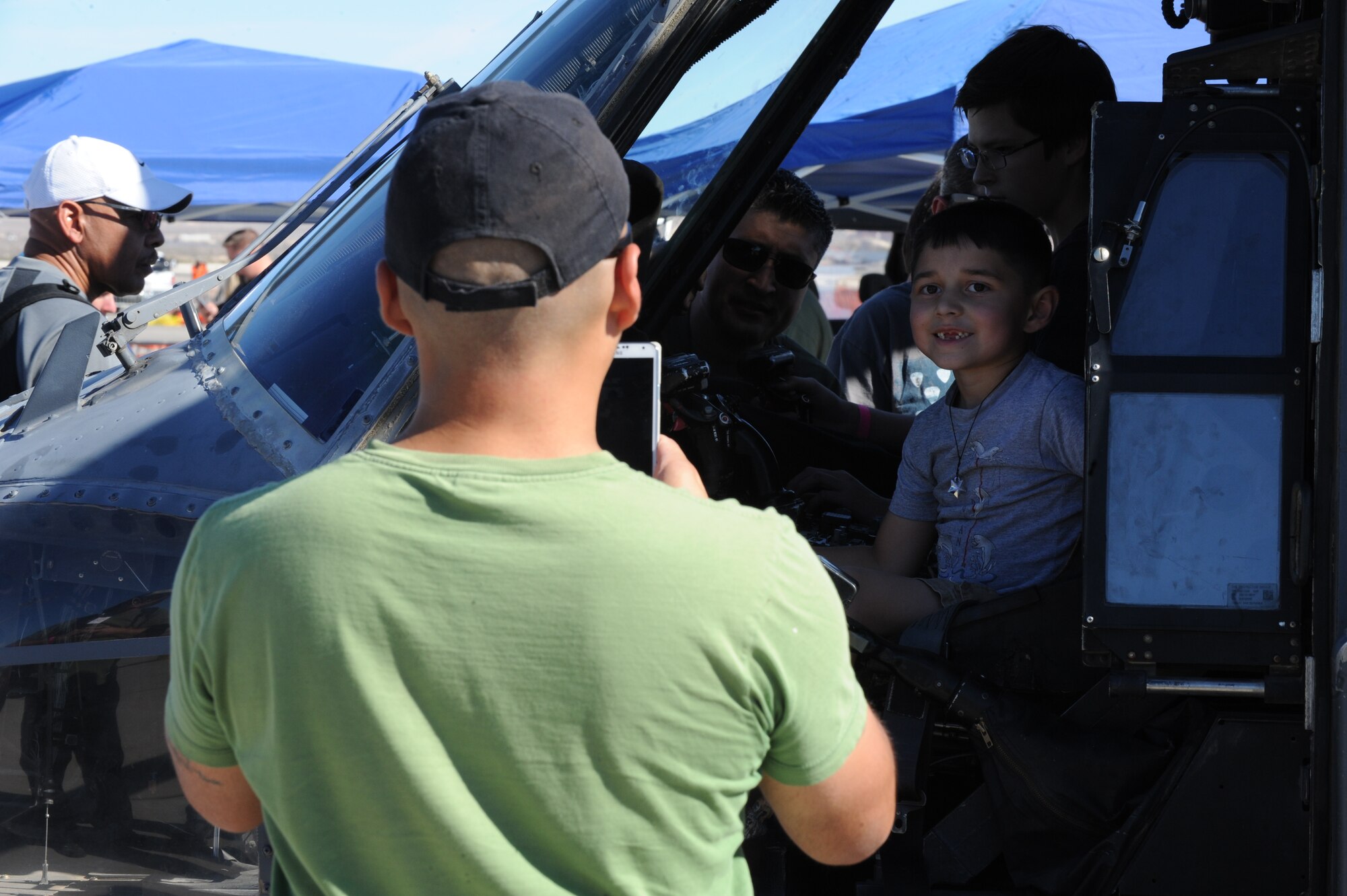 Teddy Umans snaps a photo of his son, Sebastian, while he sits in the cockpit of a 66th Rescue Squadron HH-60G Pave Hawk during the Nellis Open House at Nellis Air Force Base, Nev., Nov. 8, 2014. The 66th RQS provided both static displays and live demonstrations at this year’s open house to educate the public on their various mission sets and equipment. (U.S. Air Force photo by Airman 1st Class Joshua Kleinholz)