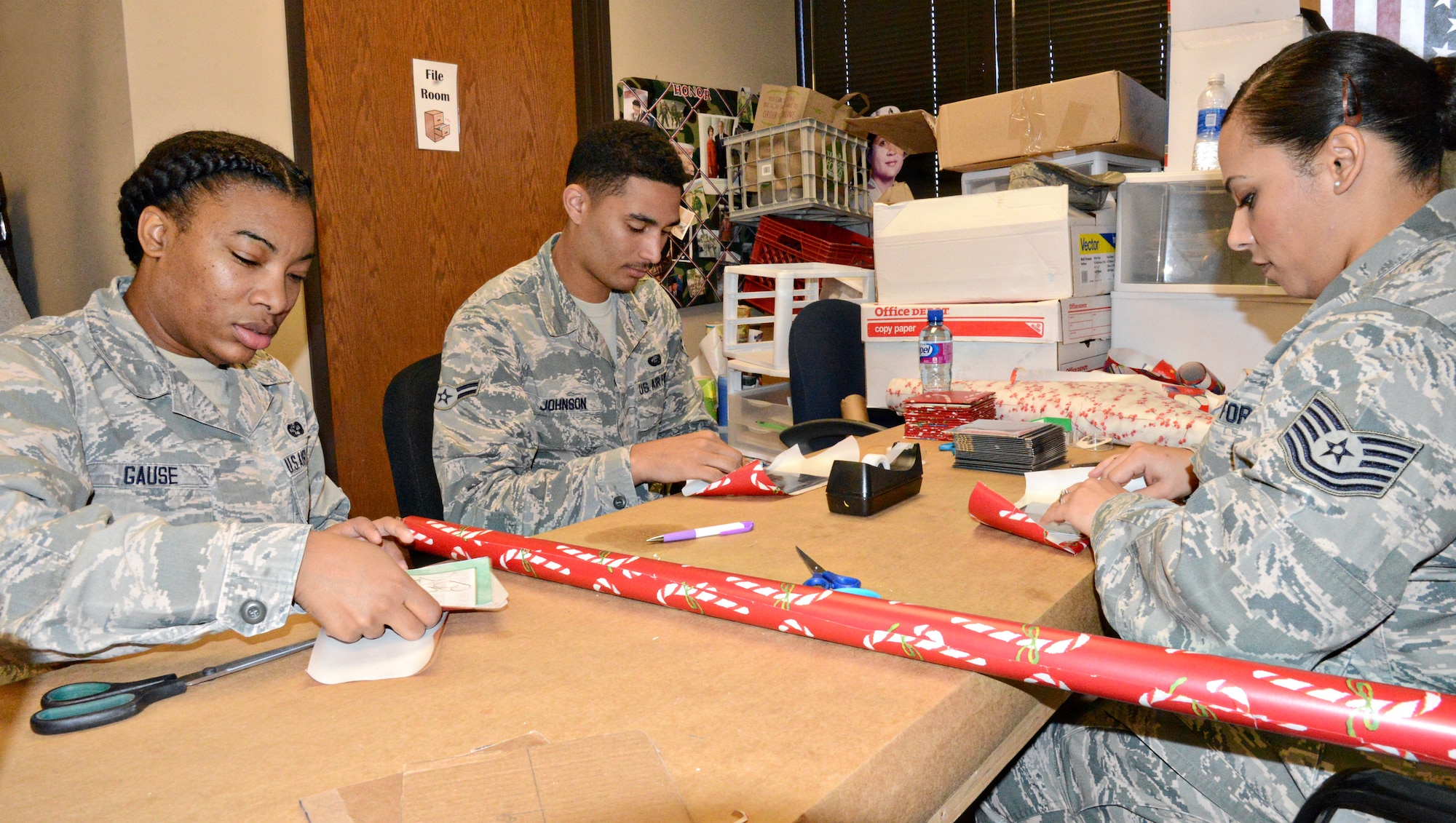 VANCE AIR FORCE BASE, Okla. -- From left, Airman 1st Class Shafiyquca Gause, from the 71st Flying Training Wing Legal Office; Airman 1st Class Torrence Johnson, from the 71st Force Support Squadron, and Tech. Sgt. Vanessa Velez, from Altus Air Force Base, wrap CDs that will be included in the care packages during a Hoops for Troops initiative with the Oklahoma City Thunder Nov. 8 at The Hugs Project, Oklahoma City. The volunteers created more than 400 care packages. (U.S. Air Force photo/Kelly White)