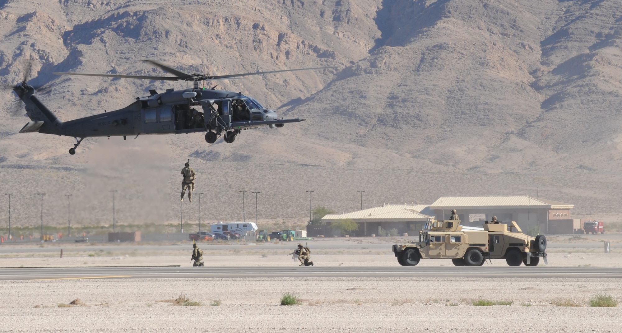 An HH-60G Pave Hawk assigned to the 66th Rescue Squadron hovers as pararescuemen of the 58th Rescue Squadron work to secure a simulated casualty during a capabilities demonstration during the Nellis Open House at Nellis Air Force Base, Nev., Nov. 8, 2014. The aircrew performed multiple demonstrations throughout the open house to educate the public on their rapid combat search and rescue capabilities. (U.S. Air Force photo by Airman 1st Class Joshua Kleinholz)
