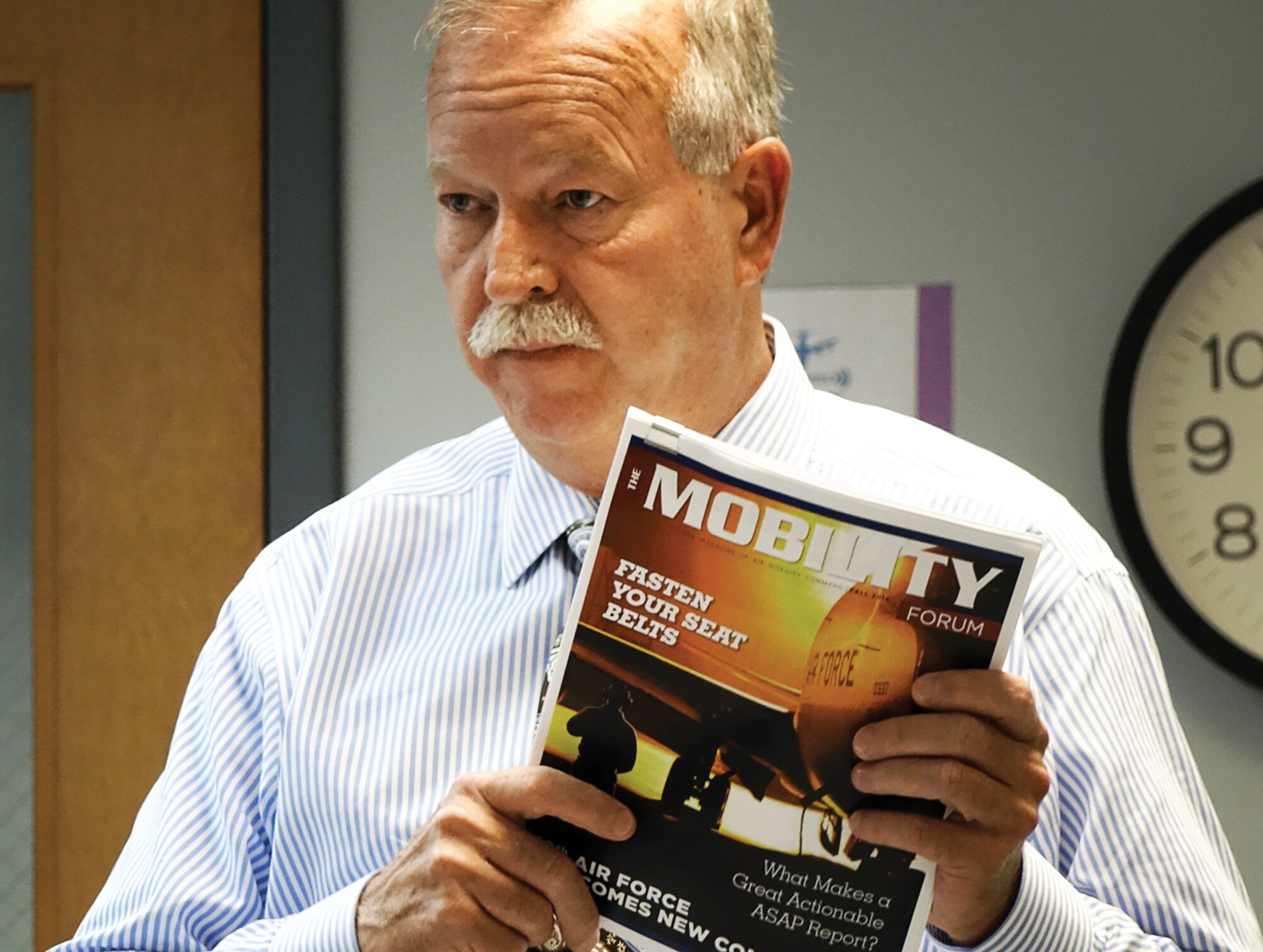 Mr. Joe Hughes Chief of AMC Ground Safety holding The Mobility Forum, Magazine of Air Mobility Command