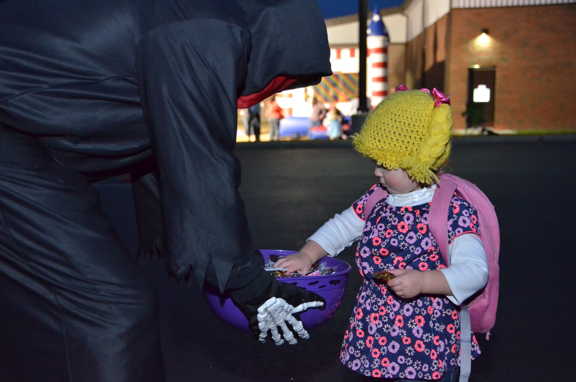 Lylah Chadbourne, 1, daughter of Tech. Sgt. Morgan Chadbourne, a resource advisor for the 103rd Maintenance Group, grabs a handful of candy form a spooky robed skeleton during the first-ever Trunk or Treat event held at Bradley Air National Guard Base, East Granby, Conn., Oct. 28, 2014.  The event was arranged by the Connecticut National Guard’s Child and Youth Program and staffed by volunteers who dressed up their car trunks with Halloween decorations. (U.S. Air National Guard photo by Tech. Sgt. Joshua Mead)