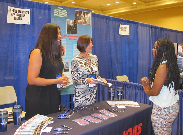 Rose Day (left) and Julia Ignacek (center) answer questions from an attendee of the 41st Annual National Organization for the Professional Advancement of Black Chemists and Chemical Engineers Conference in New Orleans Sept. 23, 2014.  Day and Ignacek are members of the Air Force Technical Applications Center, Patrick AFB, Fla.  The co-workers set up a booth to reach out to a diverse audience of scientists, educators, managers, engineers and students who attended the week-long event.  (Courtesy photo)