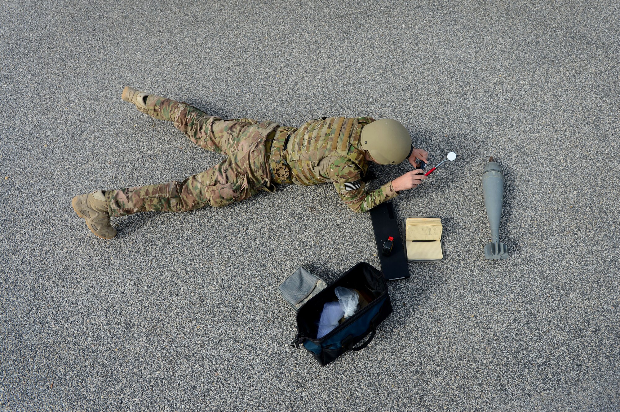 U.S. Air Force Staff Sgt. Chandler Boettcher, 20th Civil Engineer Squadron explosive ordnance disposal technician, takes pictures of a simulated unexploded ordnance during Operational Readiness Exercise Weasel Victory 15-01 at Shaw Air Force Base, S.C., Nov. 18, 2014. Boettcher photographed each part of the UXO to ensure positive identification. (U.S. Air Force photo by Airman 1st Class Jensen Stidham/Released)