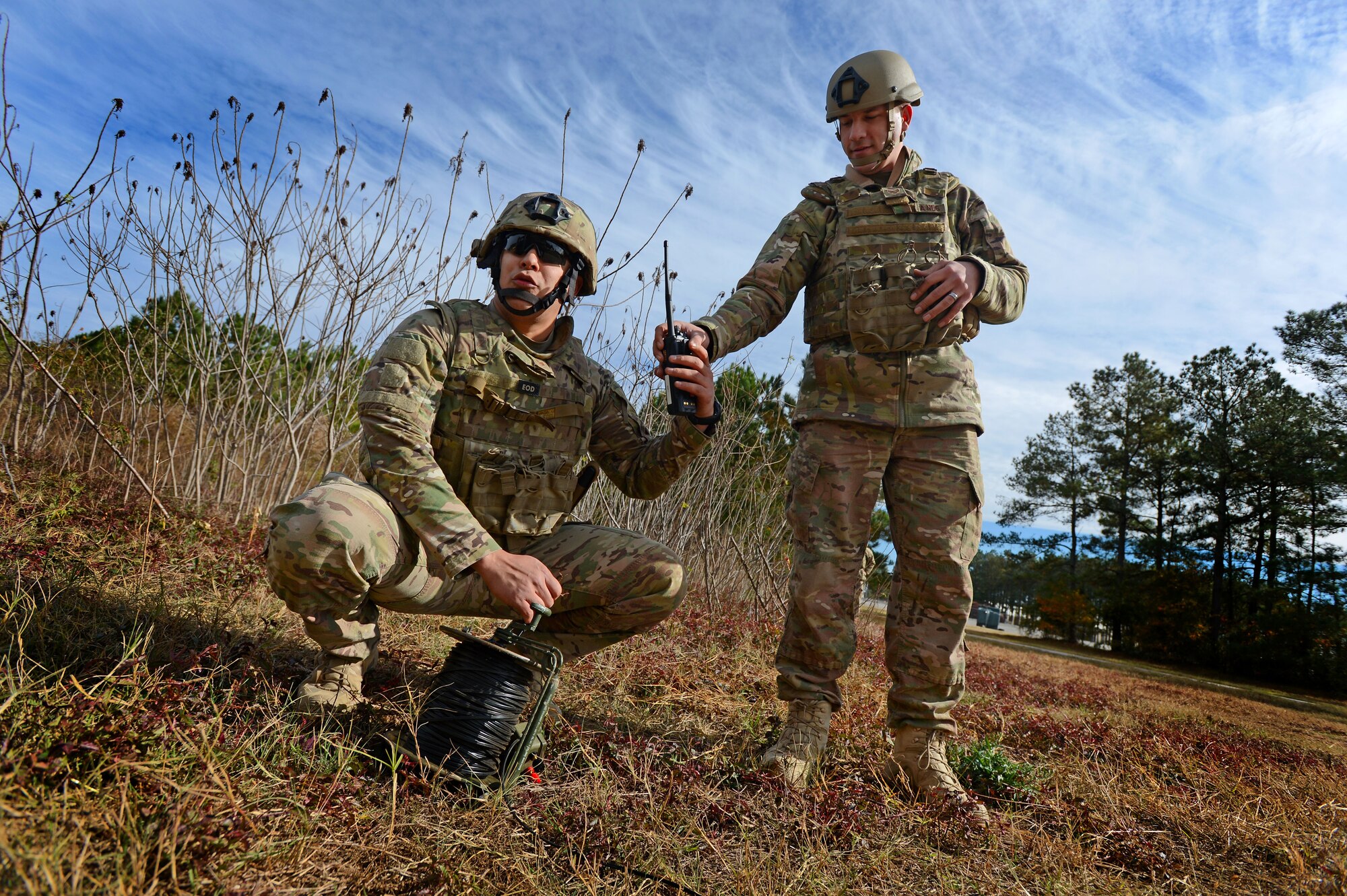 U.S. Air Force Tech. Sgt. Alan Garrison, 20th Civil Engineer Squadron explosive ordnance disposal technician, hands a land mobile radio to Staff Sgt. Ryan Nielsen 20th CES EOD technician, during Operational Readiness Exercise Weasel Victory15-01 at Shaw Air Force Base, S.C., Nov. 18, 2014. The two Airmen had previously detonated a simulated unexploded ordnance and had to call-in on the LMR to ensure the explosion area was all clear. (U.S. Air Force photo by Airman 1st Class Jensen Stidham/Released)