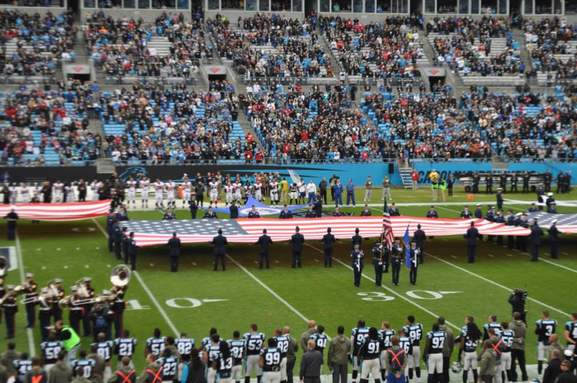 U.S. Air Force Airmen hold a United States flag during the presentation of the colors at the Carolina Panthers Salute to Service game at Bank of America Stadium, Charlotte, N.C., Nov. 16, 2014. The colors were presented by service members from all five branches of the military. (Courtesy photo)