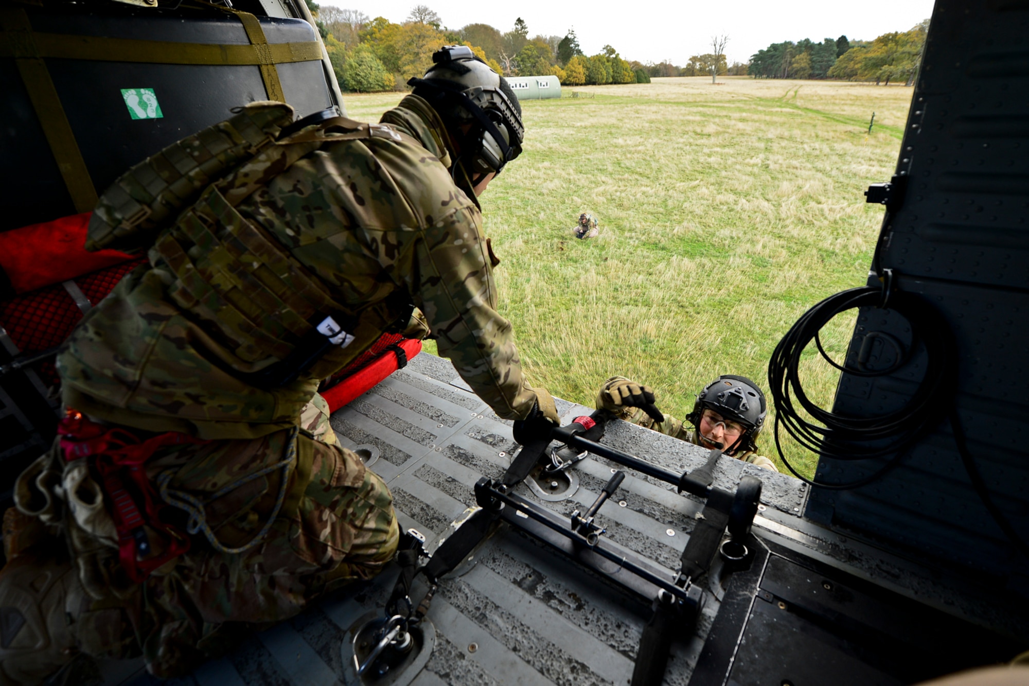 Staff Sgt. Christopher Sanders, 56th Rescue Squadron pararescueman, is helped into the helicopter by Staff. Sgt. Ryan Onley, 56th RQS pararescueman, during an alternate insertion and extractions training exercise at Royal Air Force Lakenheath, England, Nov. 12, 2014. Pararescuemen train for two years before earning their beret.  (U.S. Air Force photo by Airman 1st Class Erin R. Babis/Released)
