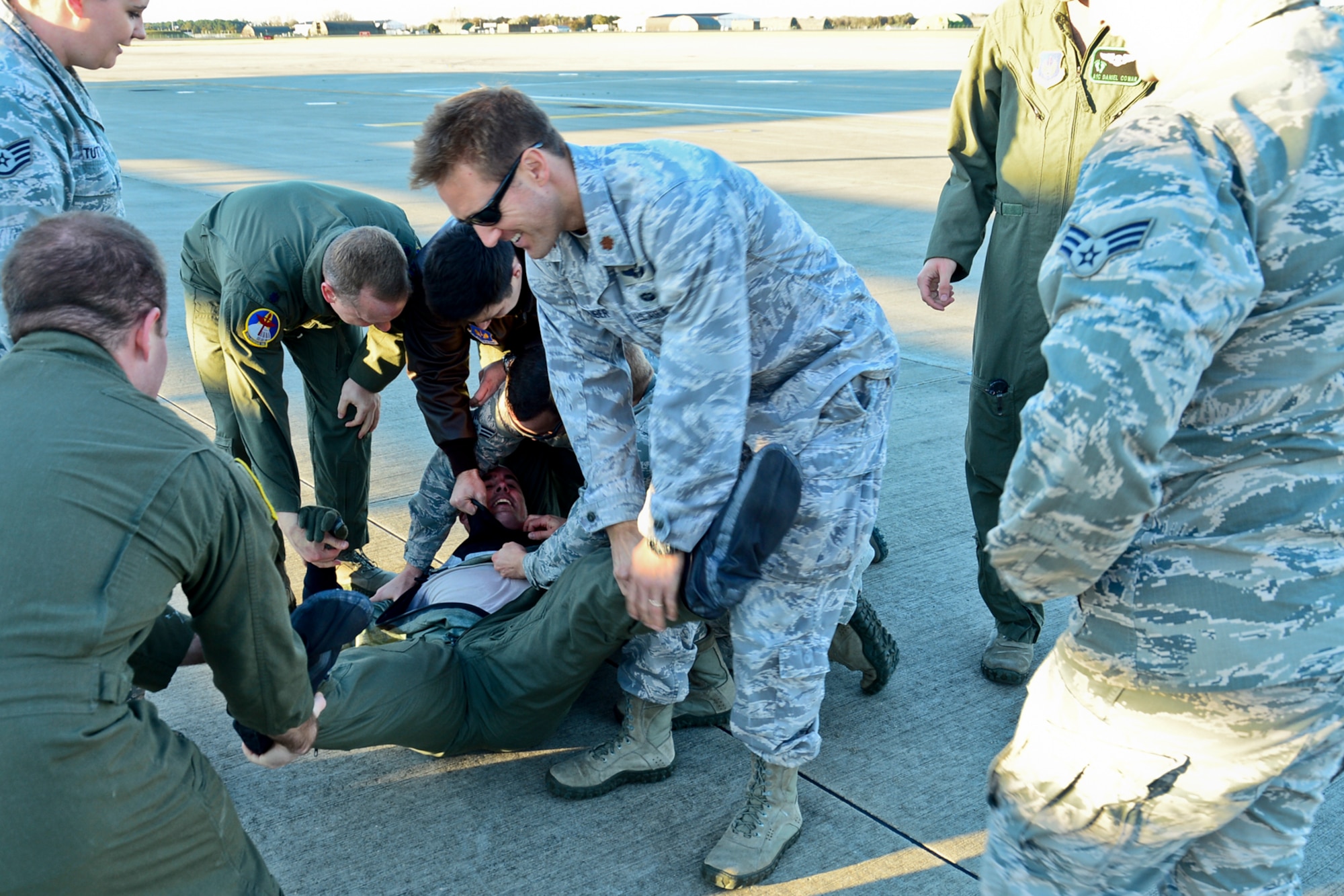 Airmen from the 56th Rescue Squadron wrestle with Capt. Robert Smith, 56th Rescue Squadron executive officer, after his fini-flight at Royal Air Force Lakenheath, England, Nov. 4, 2014. It is a tradition to capture a pilot after his final flight and paint his feet green to stamp on a ceiling tile. (U.S. Air Force photo by Airman 1st Class Erin R. Babis/Released)