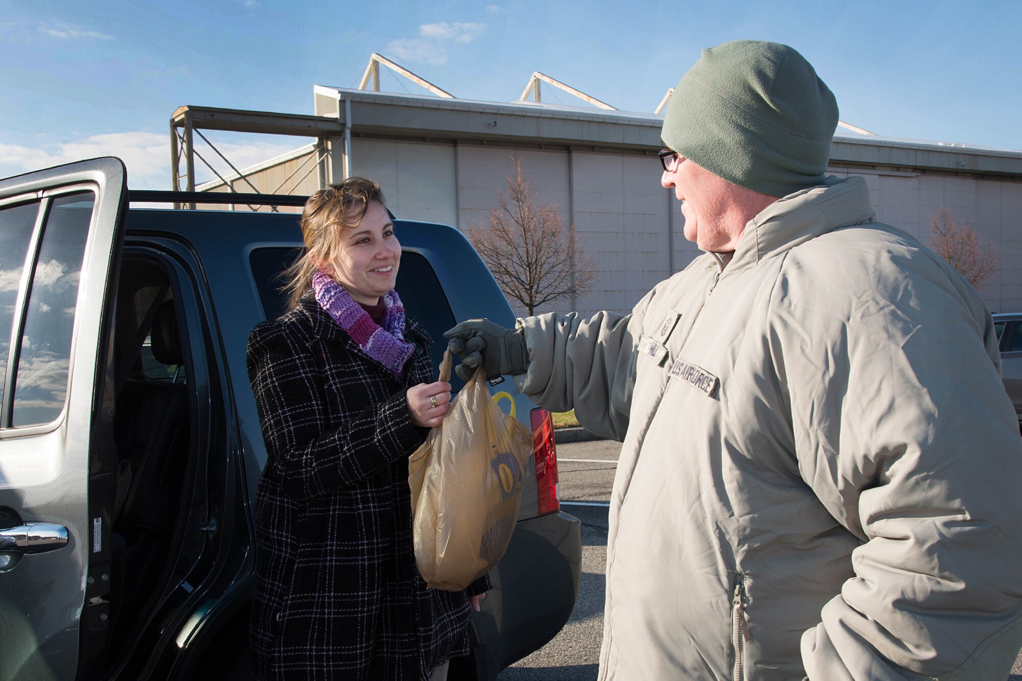 Master Sgt. Stephen Willis, 66th Security Forces Squadron fist sergeant, accepts a turkey donated from Sarah Peattie during a turkey drive in the Commissary parking lot Nov. 18. The annual event is hosted by members of the Chiefs Group, Top Three Association, and First Sergeants Council to collect turkeys for junior enlisted members and civilians in need. (U.S. Air Force photo by Mark Herlihy)