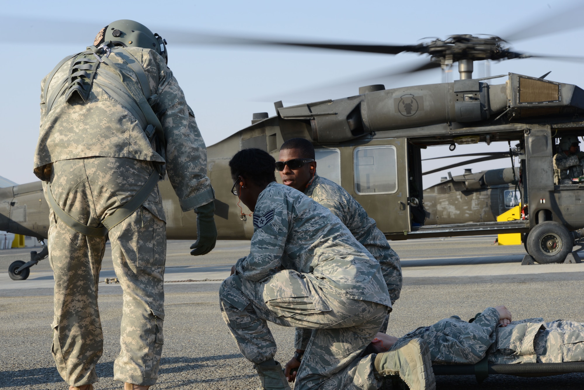 Senior Airman Dante Dubose (right), 386th Expeditionary Medical Group, prepares to give the signal to start transporting a patient to a UH-60 BlackHawk helicopter during medical evacuation training Nov. 14, 2014. Airmen from the 386th EMDG and Italian and Canadian air forces received the training Nov. 14 and 16. (U.S. Air Force photo by Tech. Sgt. Jared Marquis/released)