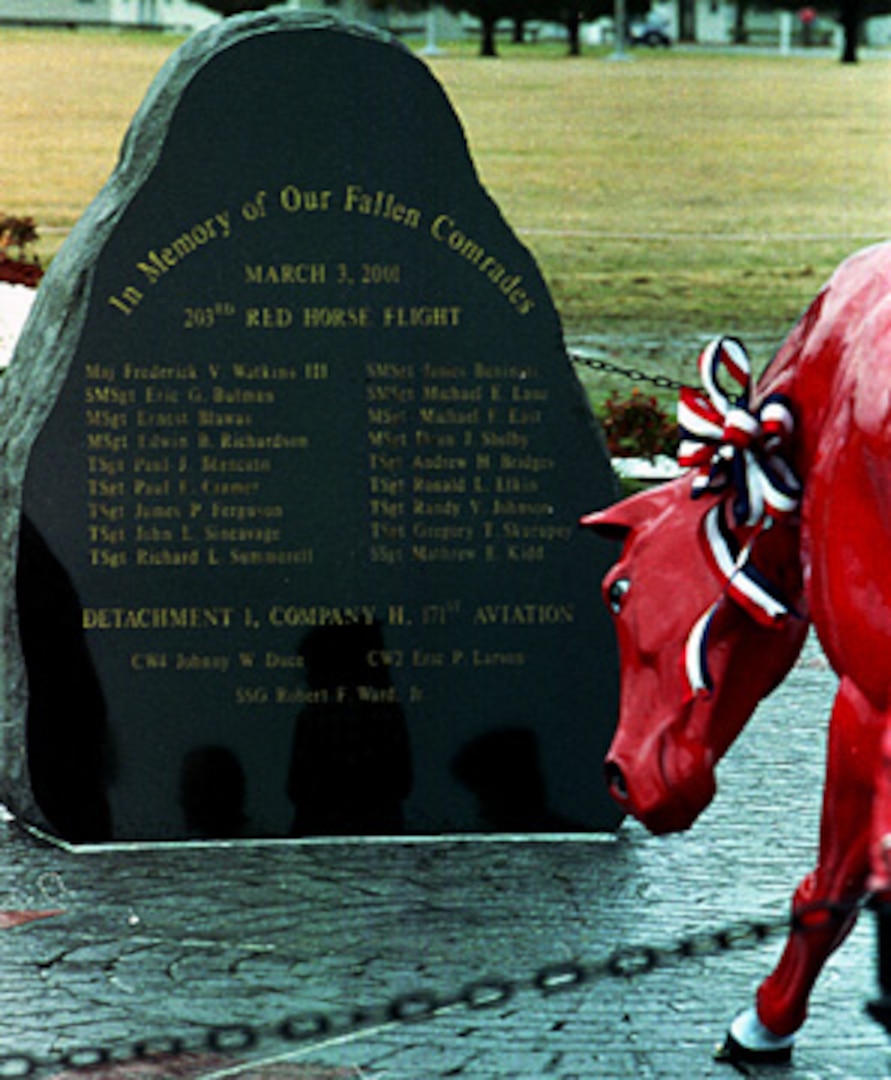 A red horse kneels in front of the 7,000-pound, black granite boulder with the names of the 21 fallen Army and Air National Guard members etched into its polished surface.