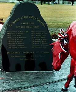 A red horse kneels in front of the 7,000-pound, black granite boulder with the names of the 21 fallen Army and Air National Guard members etched into its polished surface.