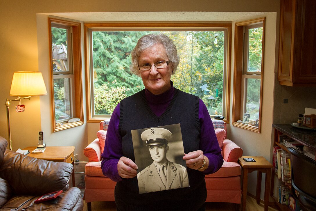 Barbara Kenney displays a photo of her late father, U.S. Marine 1st Lt. George Greeley Wells, at her home in Bellevue, Washington, Oct. 25, 2014. Greeley served as the adjutant of 2nd Battalion, 28th Marine Regiment, 5th Marine Division, during World War II’s famed Battle of Iwo Jima. He carried the first flag that was raised on Mt. Suribachi, a moment later captured by Associated Press photographer Joe Rosenthal in the war’s most famous photo. In the 1990s and early 2000s, he was featured in James Bradley’s best-selling book “Flags of Our Fathers” and “War Stories with Oliver North,” produced by the retired Marine and Fox News correspondent. Greeley, a native of Lake Forest, Illinois, moved with his family from Harding Township, New Jersey, to Bellevue in the early 2000s. At 94, he passed away in his sleep here Sept. 22, 2014. (U.S. Marine Corps photo by Sgt. Reece Lodder)