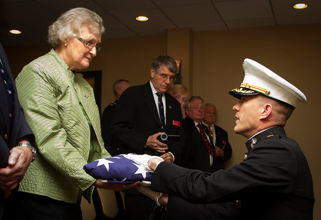 Maj. Stephen Harding, a supply officer with Combat Logistics Battalion 23, presents a flag on behalf of 35th Commandant of the Marine Corps Gen. James Amos to Barbara Kenney during a memorial service for her father, 1st Lt. George Greeley Wells, in Bellevue, Wash., Oct. 25, 2014. Greeley served as the adjutant of 2nd Battalion, 28th Marine Regiment, 5th Marine Division, during World War II’s famed Battle of Iwo Jima. He carried the first flag that was raised on Mt. Suribachi, a moment later captured by Associated Press photographer Joe Rosenthal in the war’s most famous photo. In the 1990s and early 2000s, he was featuring in James Bradley’s best-selling book “Flags of Our Fathers” and “War Stories with Oliver North,” produced by the retired Marine and Fox News correspondent. Greeley, a native of Lake Forest, Ill., moved with his family from Harding Township, N.J., to Bellevue in the early 2000s. At 94, he passed away in his sleep here Sept. 22, 2014. (U.S. Marine Corps photo by Sgt. Reece Lodder)
