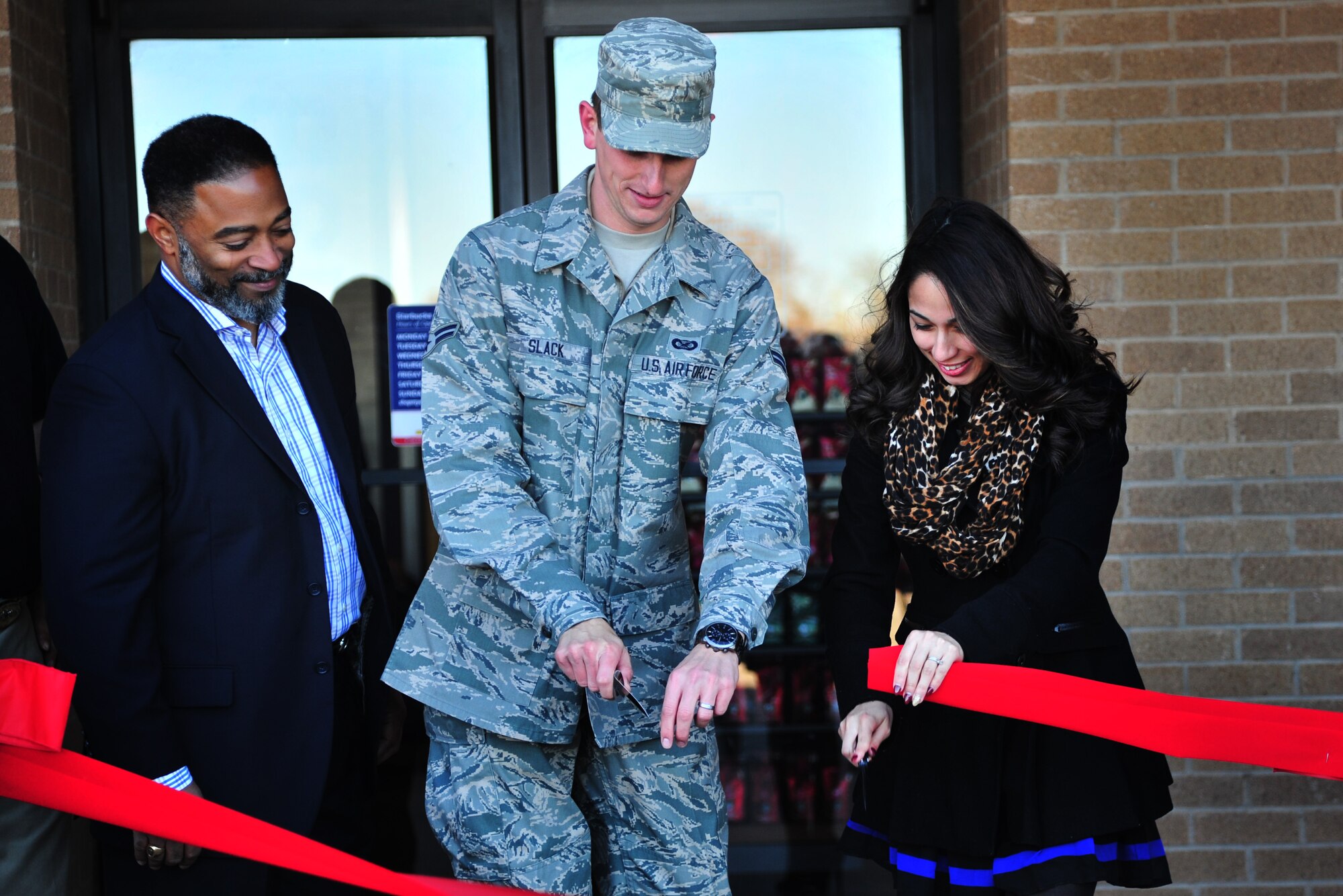 U.S. Air Force Airman 1st Class Chip Slack, 27th Special Operations Wing Public Affairs photojournalist, and Jasmine Johnson, Balfour Beattie Communities resident specialist and spouse representative, cut the ribbon at the Starbucks grand opening Nov. 20, 2014 at Cannon Air Force Base, N.M. Members of the 27 SOW hosted the officials from the Army and Air Force Exchange Services and Starbucks who helped finalize the project. (U.S. Air Force Photo/Staff Sgt. Alexxis Mercer)