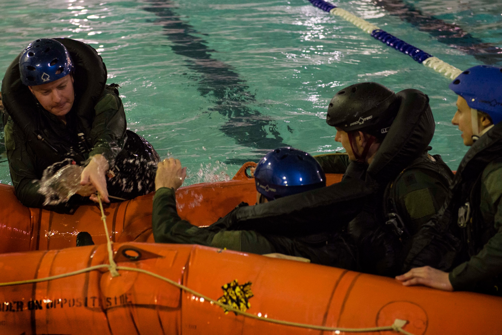 Aircrews exercise their survival skills as they climb into a life raft at the McAdoo Fitness Center pool Nov. 4, 2014, at Minot Air Force Base, N.D. The course, taught by survival, evasion, resistance, and escape instructors, teaches aviators the proper survival techniques for both water and combat zones. (U.S. Air Force photo/Airman 1st Class Lauren Pitts) 