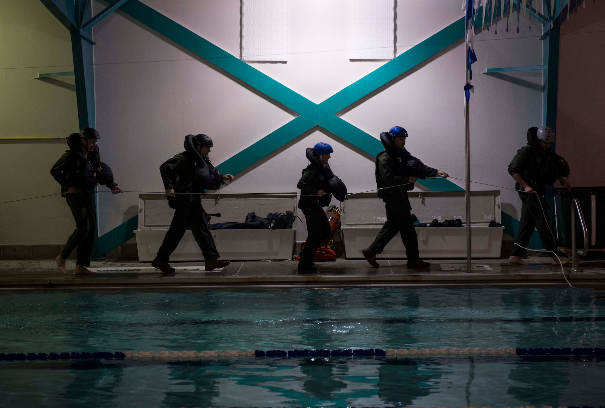 Aircrew members participating in a water and combat survival training course walk with a pulley system used to replicate the sensation of being dragged through water Nov. 4, 2014, at the Minot Air Force Base, N.D., base pool. The course teaches survival techniques for aviators in the event their aircraft were to ever crash land or be shot down over water. (U.S. Air Force photo/Airman 1st Class Lauren Pitts) 