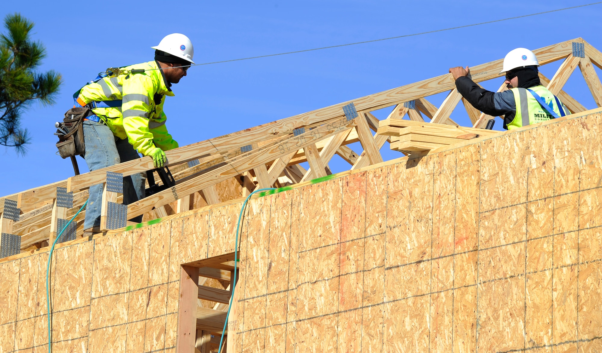 Two construction workers put up roof trusses at the Osprey Landing Neighborhood construction site on Hurlburt Field, Fla., Nov. 18, 2014. After framework is done, workers will start on the mechanicals, such as heating, ventilation, air conditioning and plumbing. (U.S. Air Force photo/Staff Sgt. Sarah Hanson)