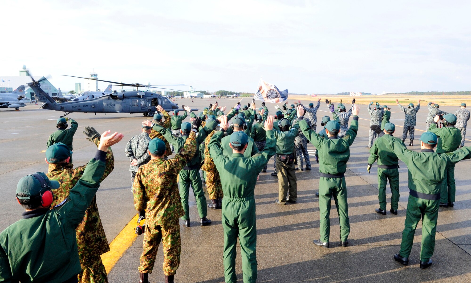 Members from the Komatsu Air Rescue Squadron wave to a 33rd Rescue Squadron HH-60G Pavehawk crew as the helicopter taxis for the last time during exercise Keen Sword at Komatsu Air Base, Nov. 16, 2014. The 33rd RQS from Kadena Air Base, Japan conducted several successful joint training missions with the Komatsu Air Rescue Squadron. The bilateral training helped form a bond between rescue crews who focused on increasing the interoperability required to respond to a potential crisis and support the defense of Japan. (U.S. Air Force photo by 2nd Lt. Erik Anthony/Released)