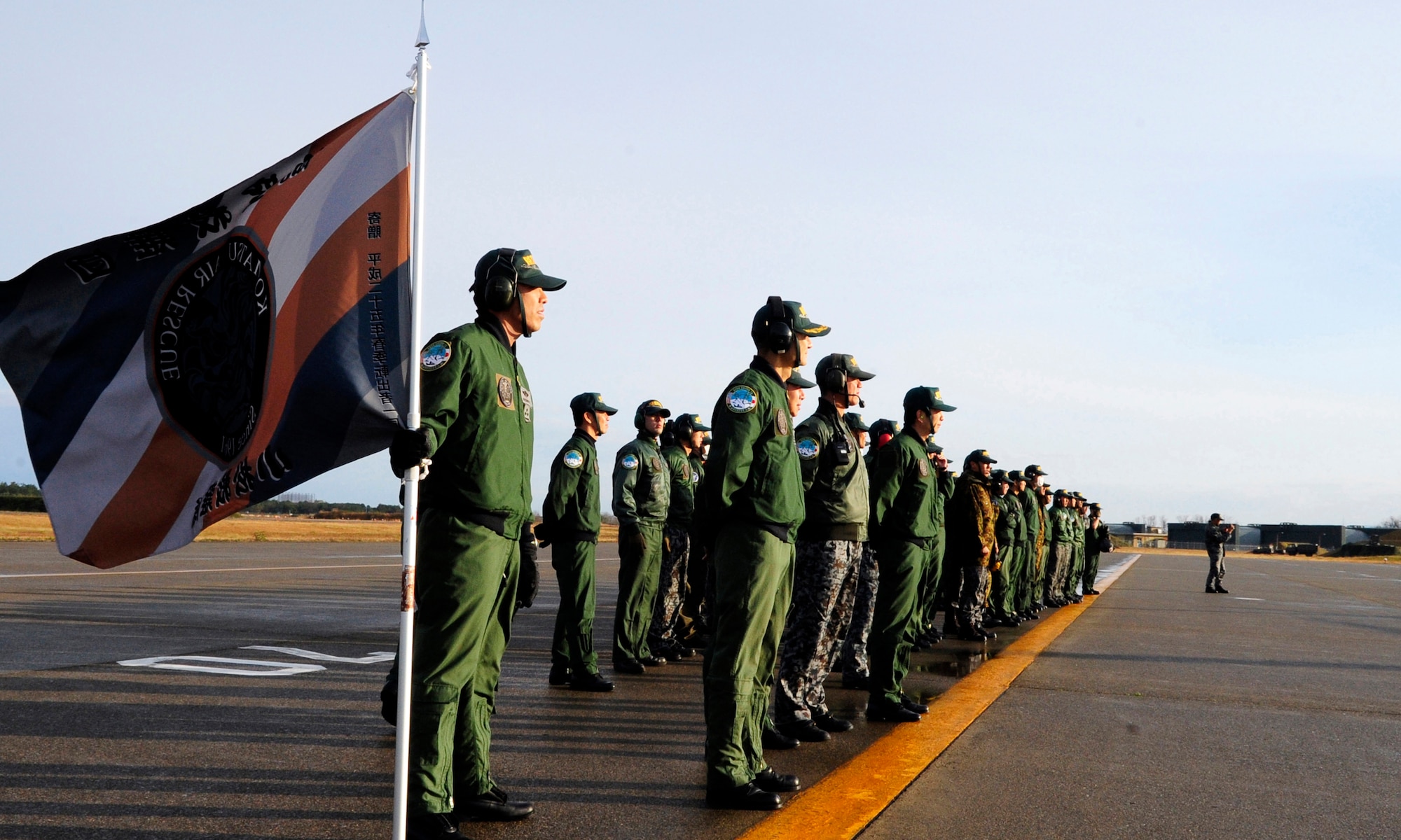 Komatsu Air Rescue Squadron personnel stand at parade rest, as they wait for the 33rd Rescue Squadron's HH-60G Pavehawks to start their engines on Komastu Air Base, Japan, Nov. 16, 2014. This concludes exercise Keen Sword for the 33rd RQS. The 33rd RQS from Kadena Air Base, Japan successfully completed multiple joint training missions with members from the Komatsu Air Rescue Squadron, increasing the interoperability required to support the defense of Japan, respond to a potential crisis and offer humanitarian assistance. (U.S. Air Force photo by 2nd Lt. Erik Anthony/Released)