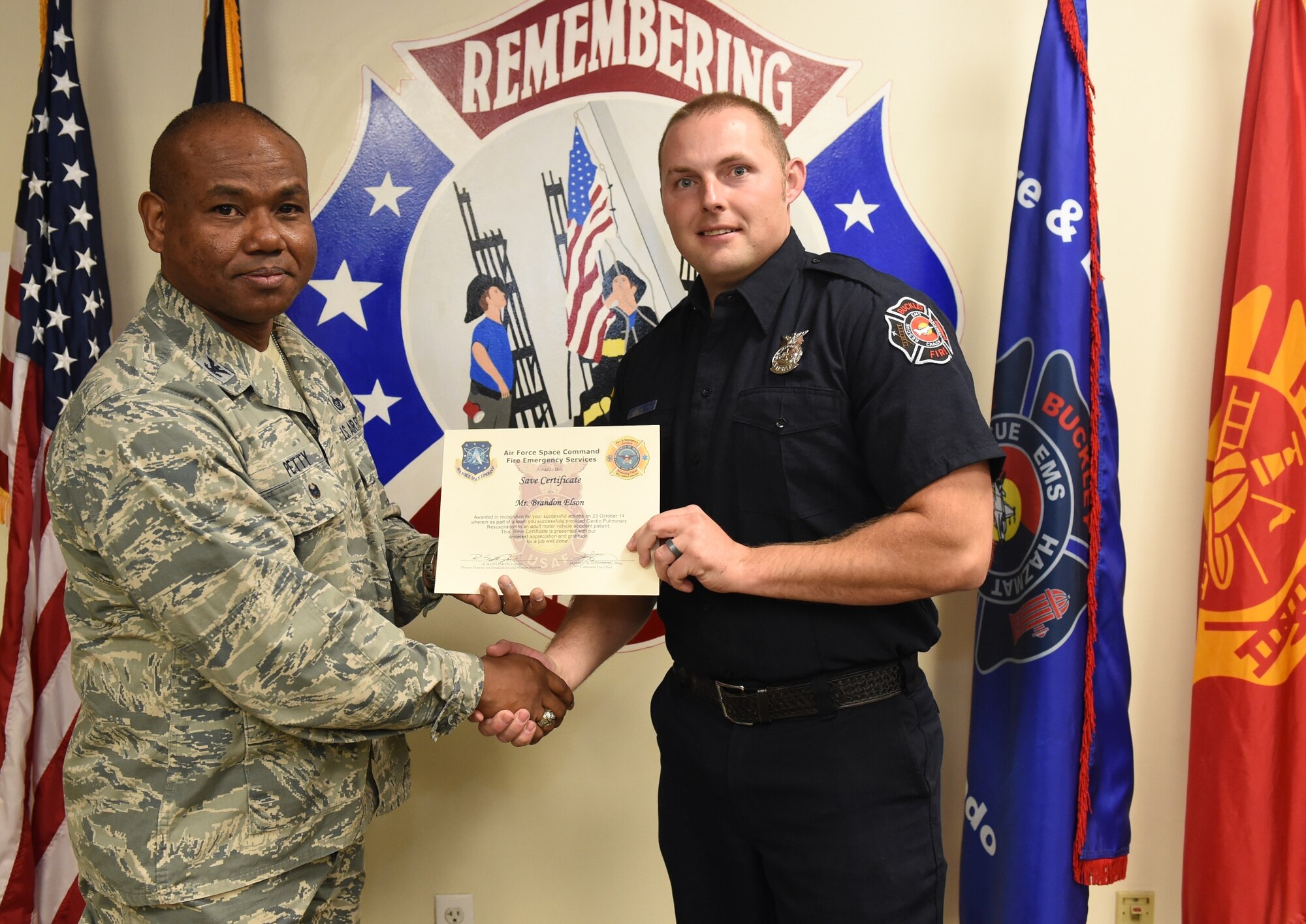 Brandon Elson, Buckley Fire Emergency Services, receives an Air Force Space Command Fire Emergency Services Save Certificate from Col. George Petty, AFSPC Civil Engineer Readiness and Emergency Management chief, Nov. 20, 2014, at the fire department on Buckley Air Force Base, Colo. Elson and three other firefighters were awarded for their lifesaving actions while responding to a major vehicle accident in October 2014. (U.S. Air Force photo by Tech. Sgt. Kali L. Gradishar/Released)