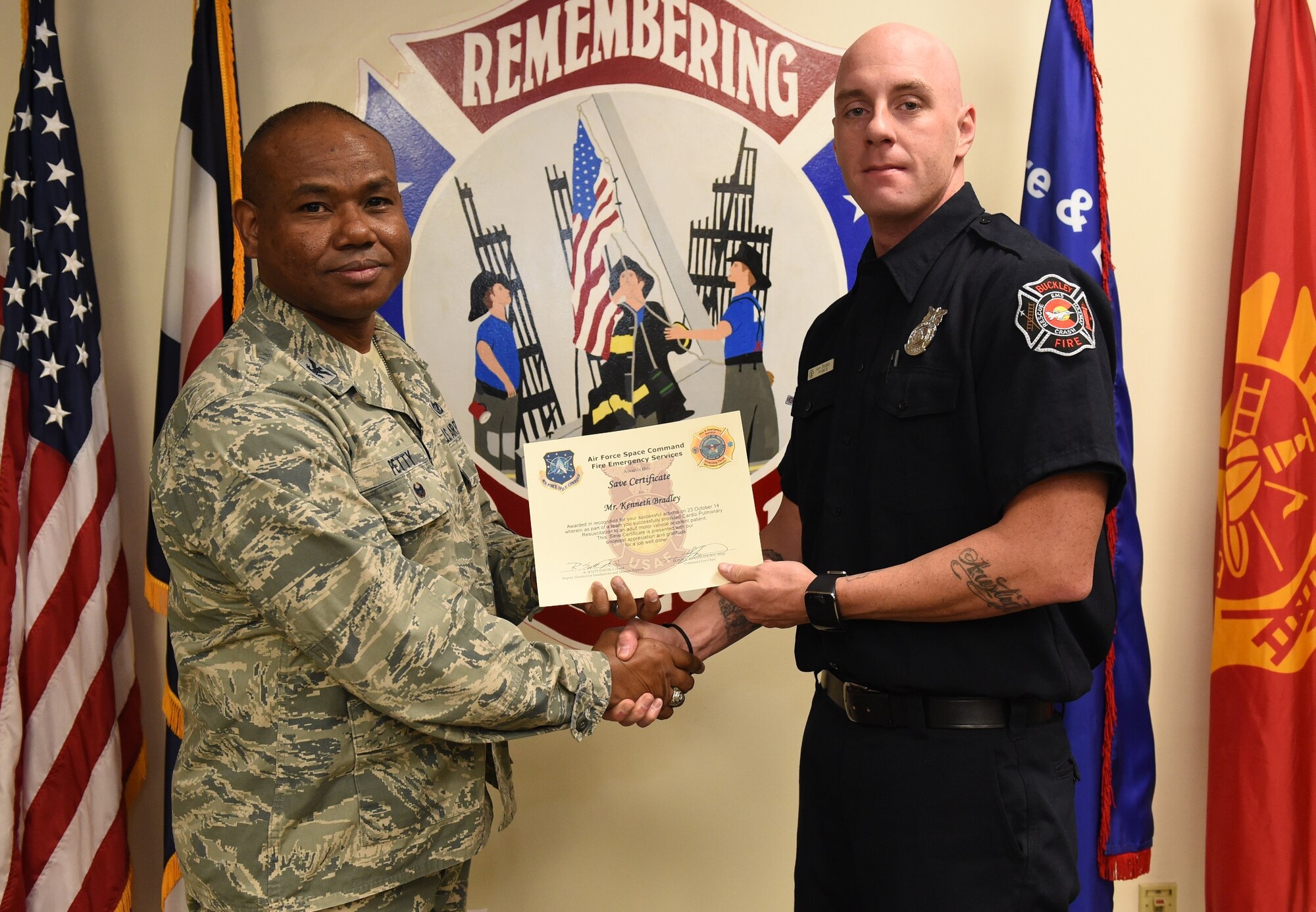 Kenneth Bradley, Buckley Fire Emergency Services, receives an Air Force Space Command Fire Emergency Services Save Certificate from Col. George Petty, AFSPC Civil Engineer Readiness and Emergency Management chief, Nov. 20, 2014, at the fire department on Buckley Air Force Base, Colo. Bradley and three other firefighters were awarded for their lifesaving actions while responding to a major vehicle accident in October 2014. (U.S. Air Force photo by Tech. Sgt. Kali L. Gradishar/Released)