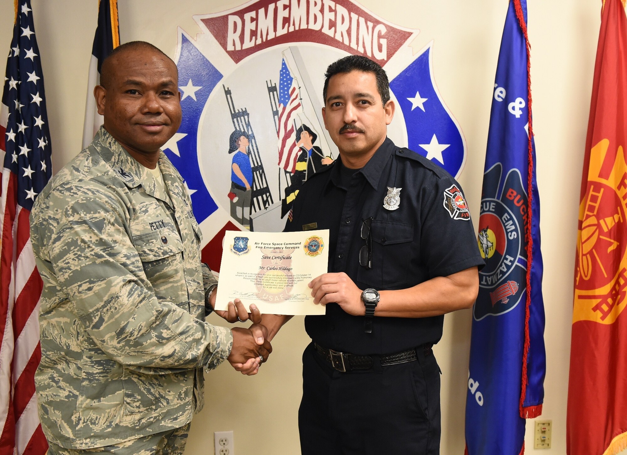 Carlos Hidalgo, Buckley Fire Emergency Services, receives an Air Force Space Command Fire Emergency Services Save Certificate from Col. George Petty, AFSPC Civil Engineer Readiness and Emergency Management chief, Nov. 20, 2014, at the fire department on Buckley Air Force Base, Colo. Hidalgo and three other firefighters were awarded for their lifesaving actions while responding to a major vehicle accident in October 2014. (U.S. Air Force photo by Tech. Sgt. Kali L. Gradishar/Released)
