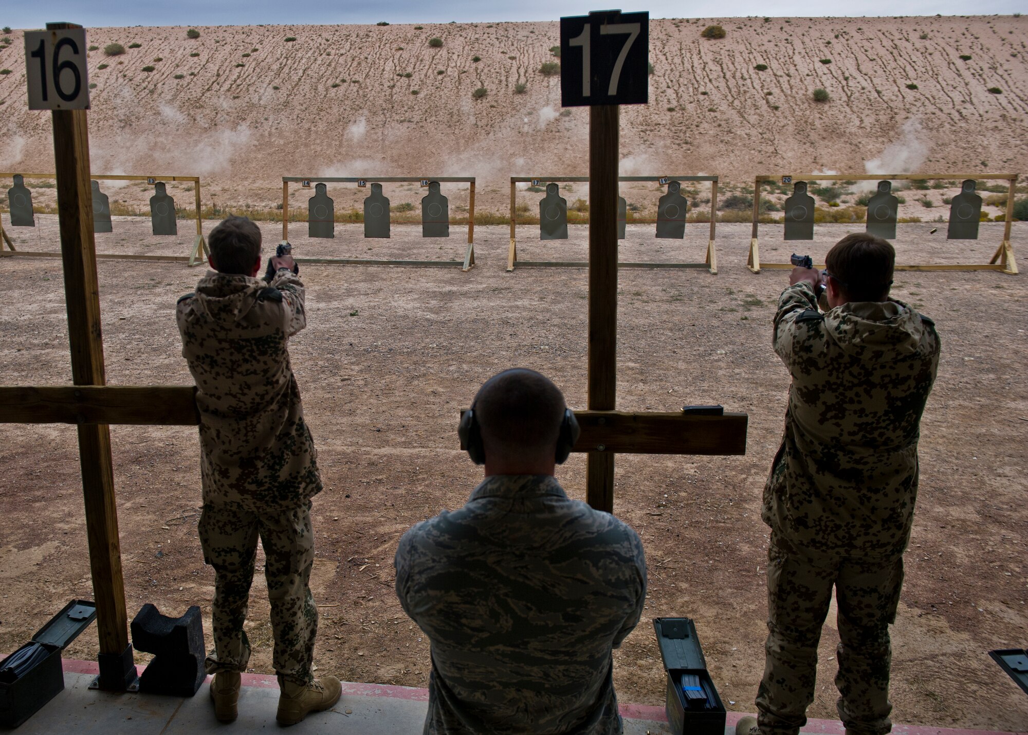 A member of the 49th Security Forces Squadron observes as the German Air Force fires the M-9 Pistol during a shooting event at Holloman Air Force Base, N.M., Nov. 12. The teambuilding event hosted both the American and German Air Force at the Combat Arms Training and Maintenance facility, where both countries had the opportunity to fire various weapons. Over 25 participants from both countries qualified with the chance to receive marksmanship on foreign pistols and rifles. The event was also an opportunity to build on an already established bond between Holloman and German Airmen. (U.S. Air Force photo by Senior Airman Leah Ferrante/released)