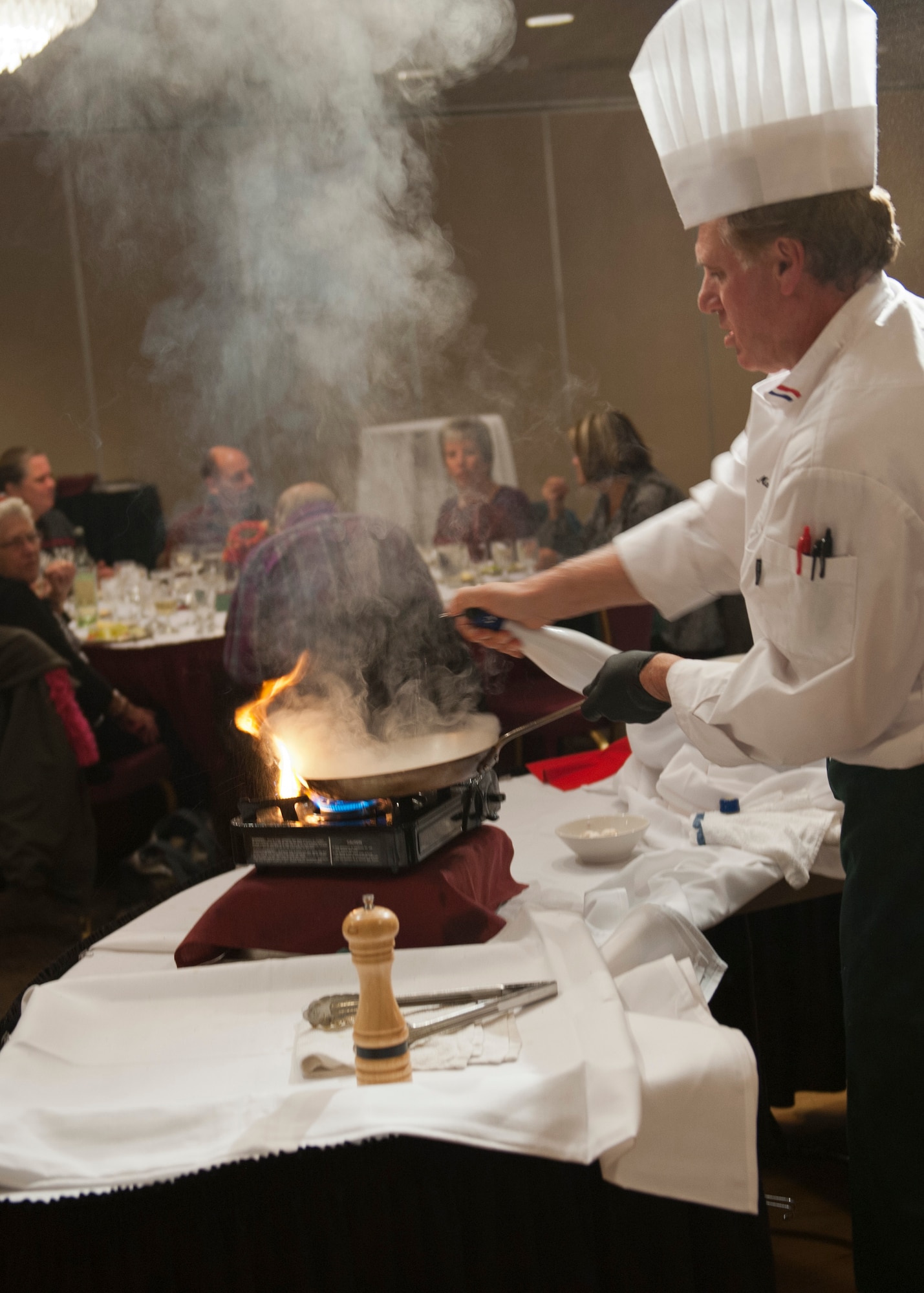 PETERSON AIR FORCE BASE, Colo. – Chef Mark Painter, certified executive chef and instructor at Pikes Peak Community College, impresses guests by using wine to create a fire while giving a demonstration at the Celebrity Guest Chef Dinner at the Club Nov. 14. Guests paid $45 to experience a gourmet four course meal prepared by Painter and see a demonstration of how a few of the dishes were created. (U.S. Air Force photo/Airman 1st Class Rose Gudex)
