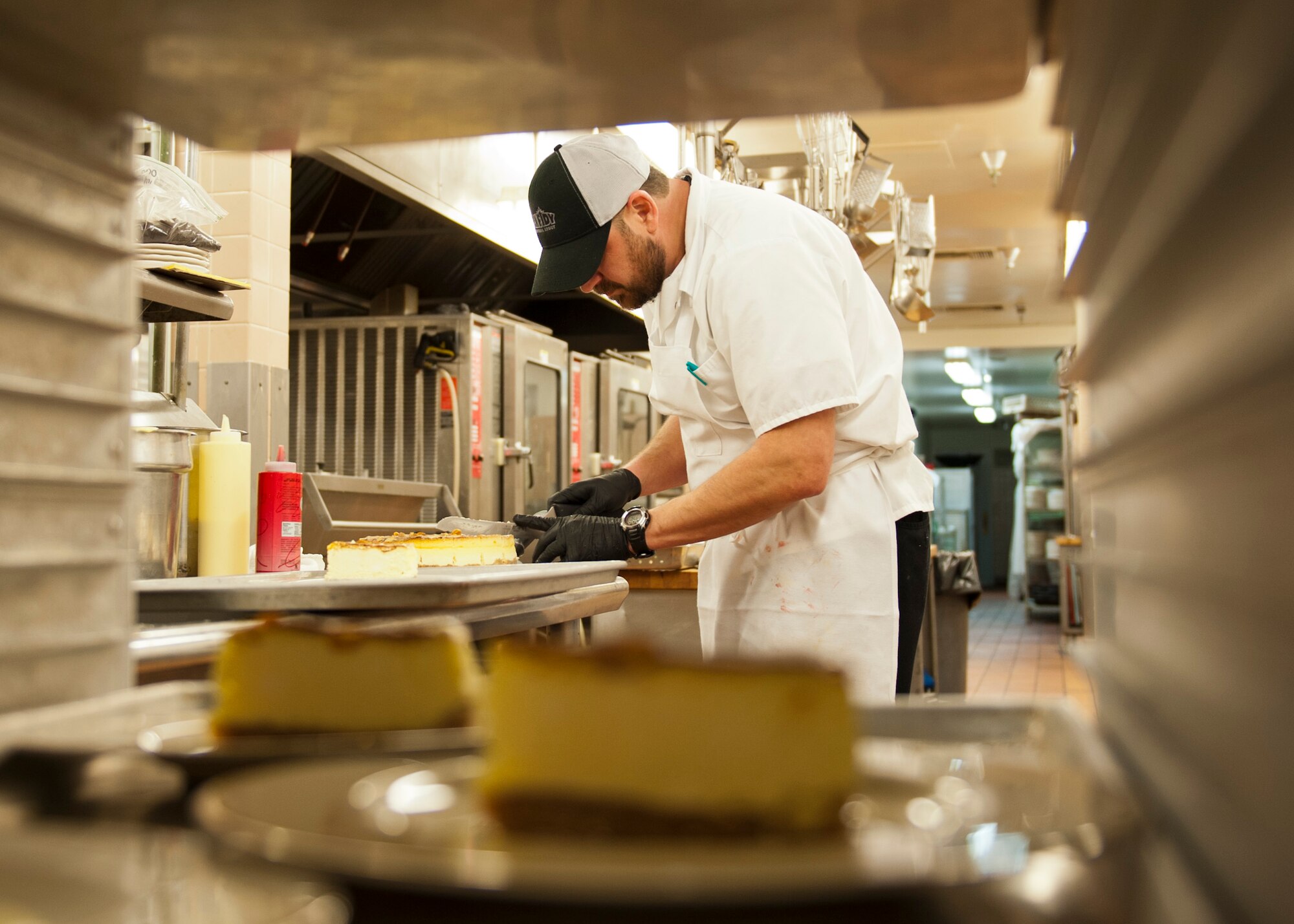PETERSON AIR FORCE BASE, Colo. – Joe Zamora, executive chef at the Club, cuts cheesecake before decorating each piece for the Celebrity Guest Chef Dinner held at the Club Nov. 14. Guests paid $45 to experience a gourmet four course meal prepared by Chef Mark Painter, certified executive chef and instructor at Pikes Peak Community College, and see a demonstration of how a few of the dishes were created. (U.S. Air Force photo/Airman 1st Class Rose Gudex)