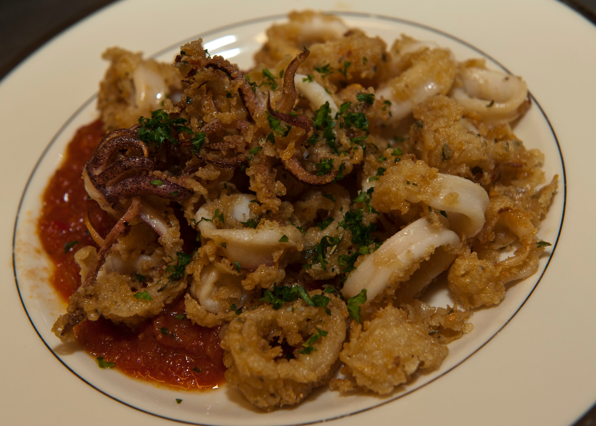 PETERSON AIR FORCE BASE, Colo. – A plate of black pepper calamari with spicy pomodoro sauce is ready to be served at the Celebrity Guest Chef Dinner at the Club Nov. 14. Guests paid $45 to experience a gourmet four course meal prepared by Chef Mark Painter, certified executive chef and instructor at Pikes Peak Community College, and see a demonstration of how a few of the dishes were created. (U.S. Air Force photo/Airman 1st Class Rose Gudex)