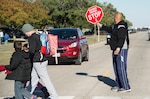 John Collins, Randolph Elementary School teacher’s aide, holds a stop sign to allow parents and their children to safely cross the street Nov. 17 at Joint Base San Antonio, Texas. The 902nd Security Forces Squadron is stepping up its patrols because of speeding problems that pose safety risks to children boarding school buses.  Be alert. Children are unpredictable. Children walking to or from school are usually very comfortable with their surroundings. This makes them more likely to take risks, ignore hazards or fail to look both ways when crossing the street. Drivers are urged to always watch for children crossing traffic lanes, observe school zone speed limits, instructions of crossing guards and use caution when traveling through school zones or near routes used by children. 