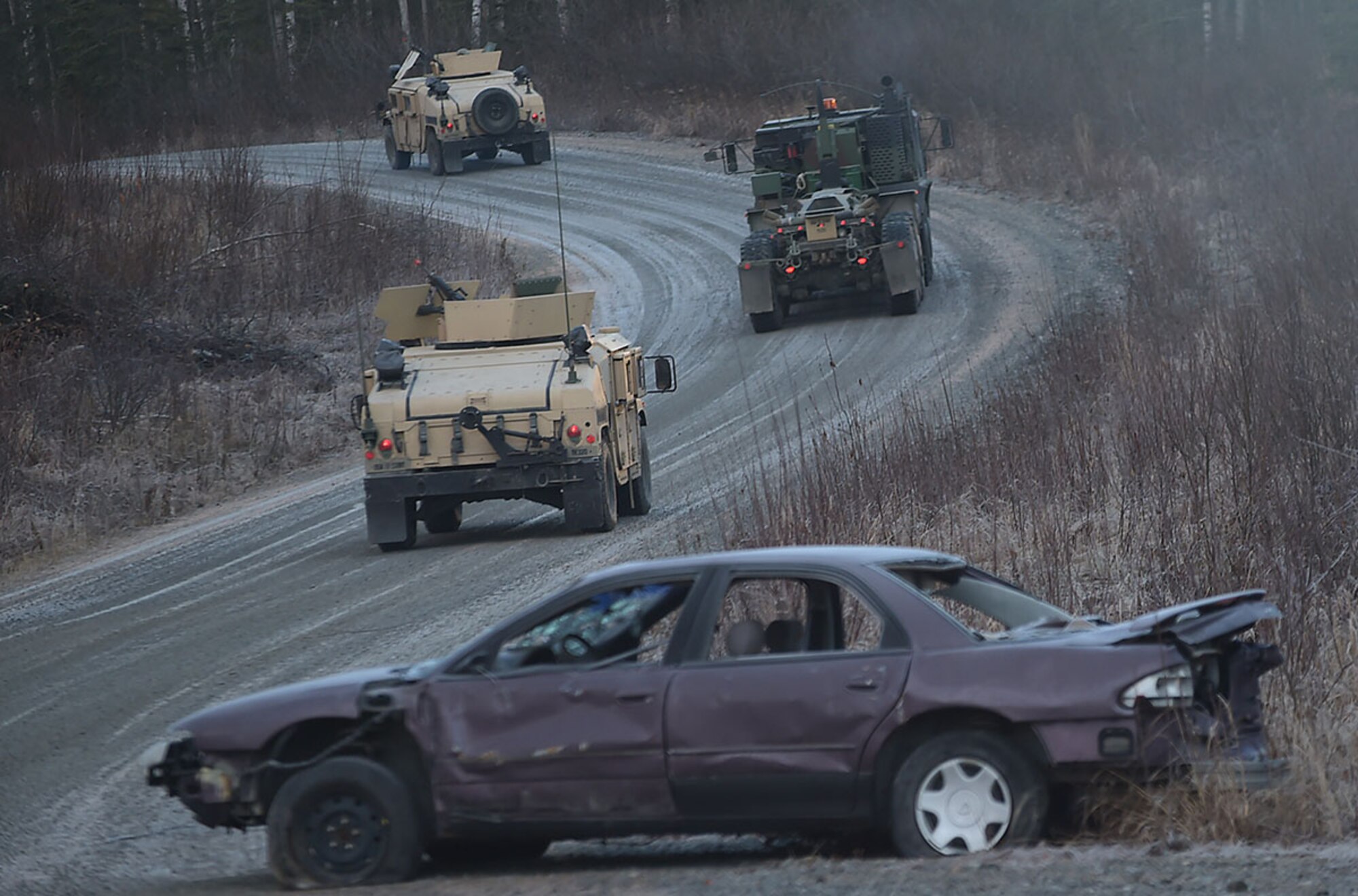 Soldiers assigned to U.S. Army Alaska's 109th Transportation Company drive past a destroyed vehicle, Thursday, Nov. 13, 2014, on Joint Base Elmendorf-Richardson, Alaska, during a convoy live-fire exercise. The soldiers also simultaneously executed react-to-ambush procedures with follow-on hasty and deliberate vehicle recovery operations. (U.S. Air Force photo/Justin Connaher)