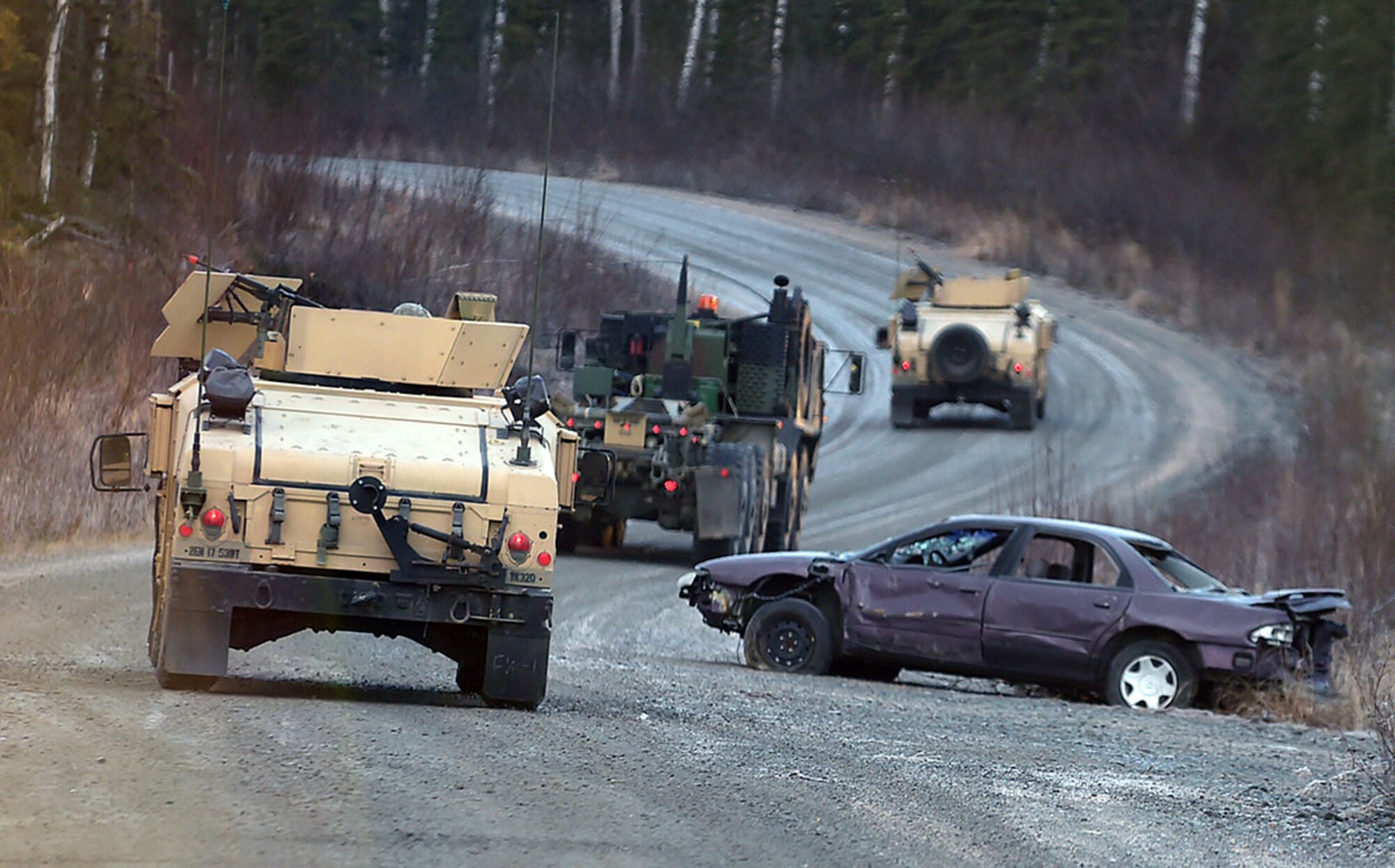 Soldiers assigned to U.S. Army Alaska's 109th Transportation Company drive past a destroyed vehicle, Thursday, Nov. 13, 2014, on Joint Base Elmendorf-Richardson, Alaska, while training for a convoy live-fire exercise. The soldiers also simultaneously executed react-to-ambush procedures with follow-on hasty and deliberate vehicle recovery operations. (U.S. Air Force photo/Justin Connaher)