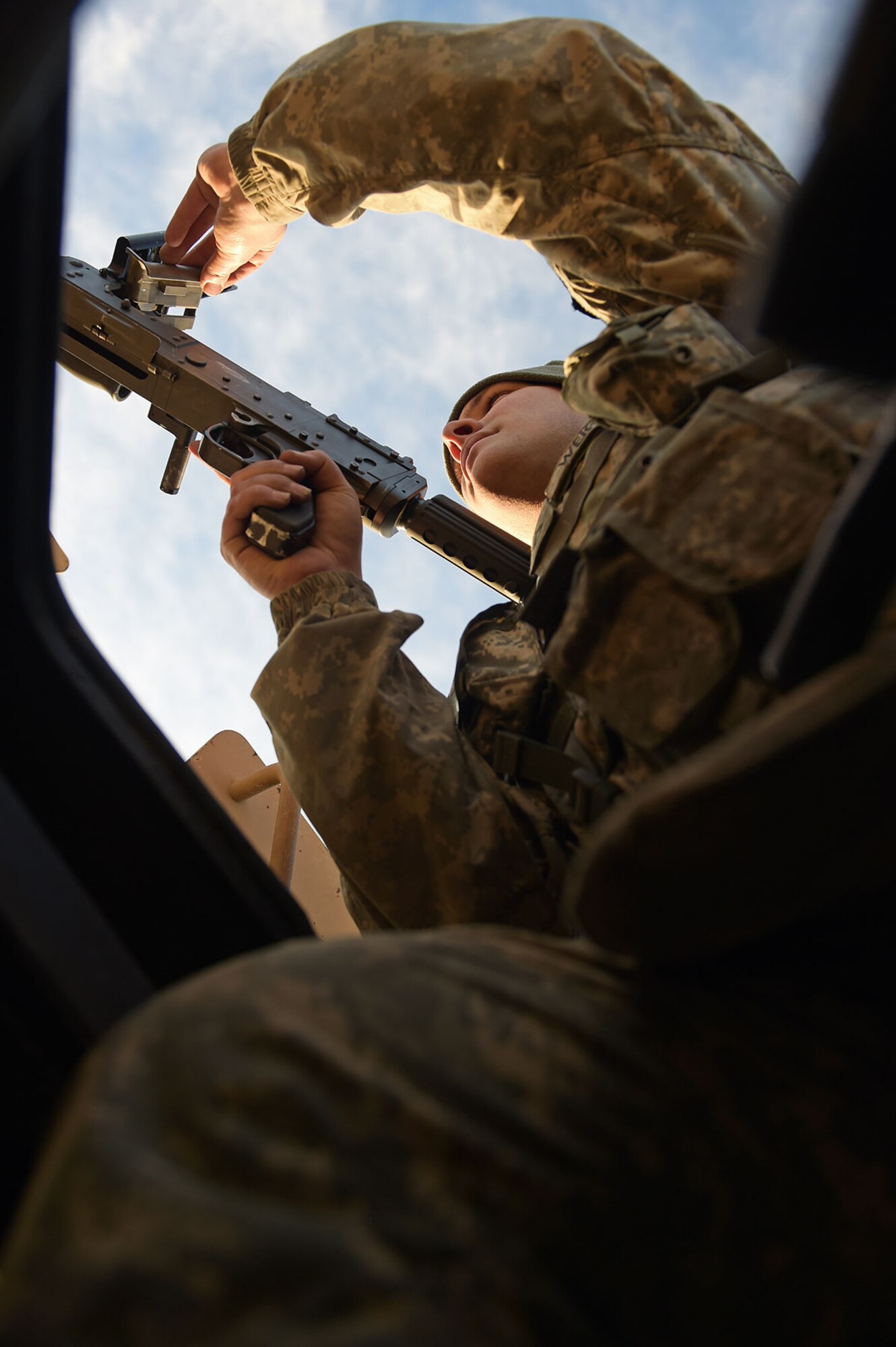 Army Pfc. Jared Weigant, a native of Red Oak, Texas, assigned to U.S. Army Alaska's 109th Transportation Company, inspects the feed tray of his machine gun, Thursday, Nov. 13, 2014, on Joint Base Elmendorf-Richardson, Alaska, as part of a convoy live-fire exercise. The soldiers also simultaneously executed react-to-ambush procedures with follow-on hasty and deliberate vehicle recovery operations. (U.S. Air Force photo/Justin Connaher)