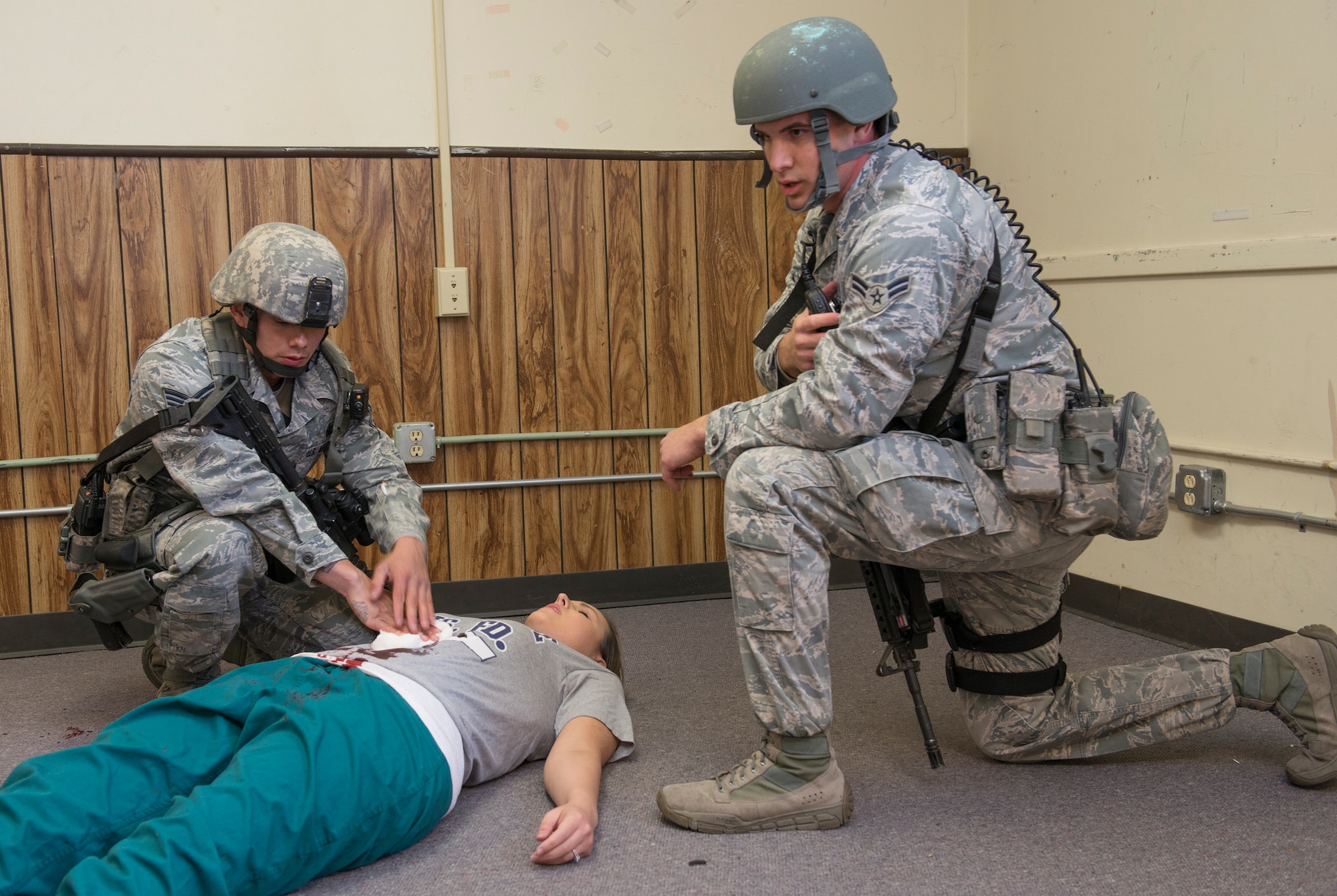 Airmen from the 60th Security Forces Squadron assess simulated victims that had been wounded during an active-shooter exercise Nov. 18, 2014, at Travis Air Force Base, California. The wounded received a card indicating their injuries with descriptions and their vital signs to advise medical responders how to treat each "victim."  (U.S. Air Force photo by Heide Couch)