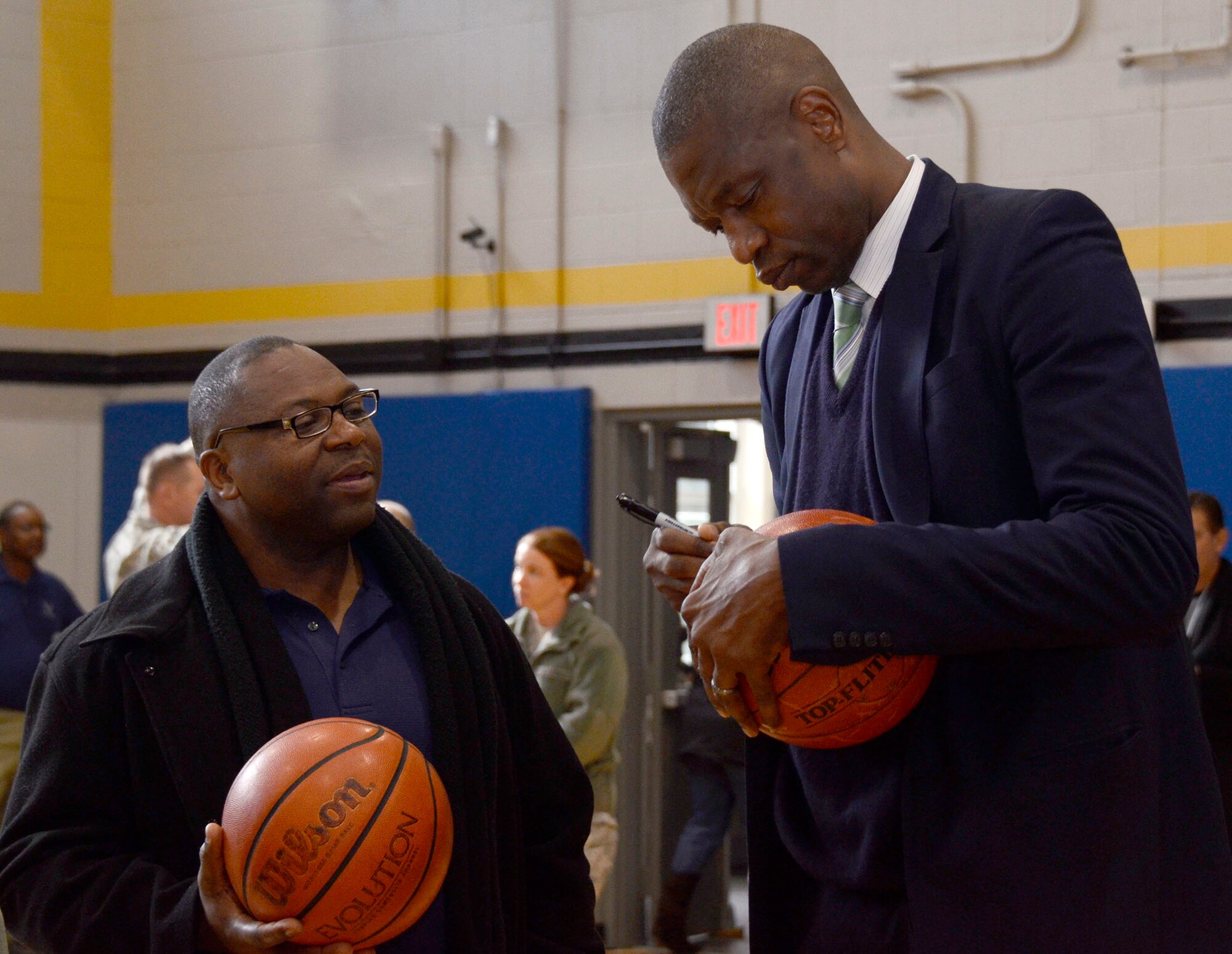 Dikembe Mutombo, NBA Hall of Famer, signs a basketball for a member of Team Dobbins at the grand opening of the renovated fitness center at Dobbins Air Reserve Base, Ga. Nov. 18, 2014. The fitness center includes approximately 30 new pieces of equipment. (U.S. Air Force photo by Don Peek/Released)