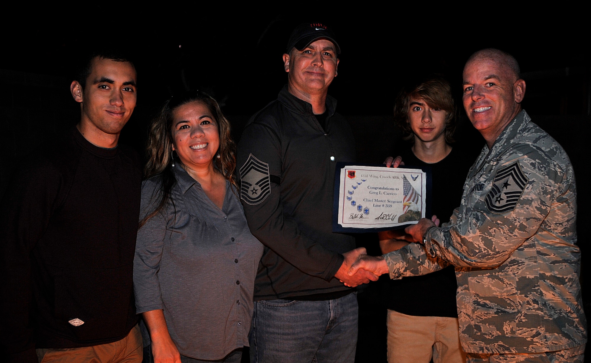 Senior Master Sgt. Greg Carrico, center, poses with his family and Chief Master Sgt. Butch Brien, 432nd Wing command chief, in Las Vegas Nov. 19, 2014.  Carrico was recently selected for promotion to chief master sergeant and Creech leadership recognized the achievement with a surprise visit to his home. (U.S. Air Force Photo by Airman 1st Class Christian Clausen/released)