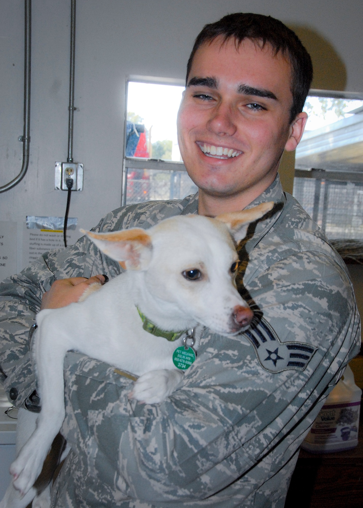 Senior Airman Mike Rodcay, of the 68th Electronic Warfare Squadron, stops by the Pet Welfare Center to adopt Baxter, a terrier mix.  The center places nearly 300 abandoned, stray and homeless cats and dogs every year.  (U.S. Air Force photo/Kevin Gaddie)