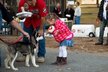 Abigail Marquis, daughter of U.S. Air Force Tech. Sgt. Zachary Marquis, 23d Maintenance Operations Flight, meets a Husky puppy at Weapons Fest Nov. 15, 2014, at Grassy Pond in Lake Park, Ga. This was the first time Moody has held a Weapons Fest. (U.S. Air Force photo by Airman 1st Class Ryan Callaghan/Released)