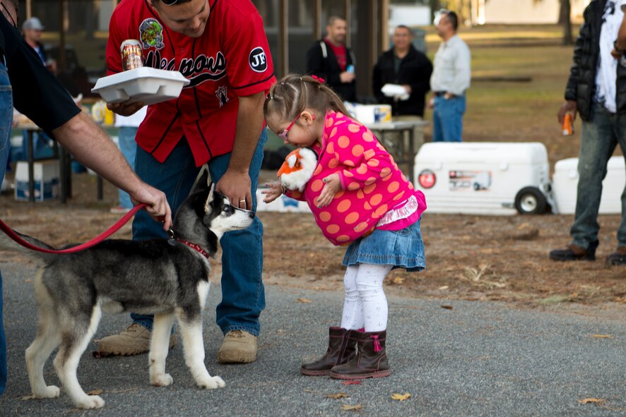 Abigail Marquis, daughter of U.S. Air Force Tech. Sgt. Zachary Marquis, 23d Maintenance Operations Flight, meets a Husky puppy at Weapons Fest Nov. 15, 2014, at Grassy Pond in Lake Park, Ga. This was the first time Moody has held a Weapons Fest. (U.S. Air Force photo by Airman 1st Class Ryan Callaghan/Released)