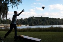 U.S. Air Force Staff Sgt. Michael Polson, 74th Aircraft Maintenance Unit weapons load crew team chief, plays cornhole during Weapons Fest Nov. 15, 2014, at Grassy Pond in Lake Park, Ga. Weapons Fest had games and activities for attendees including cornhole, bounce houses, tug-of-war and a training-bomb toss. (U.S. Air Force photo by Airman 1st Class Ryan Callaghan/Released)