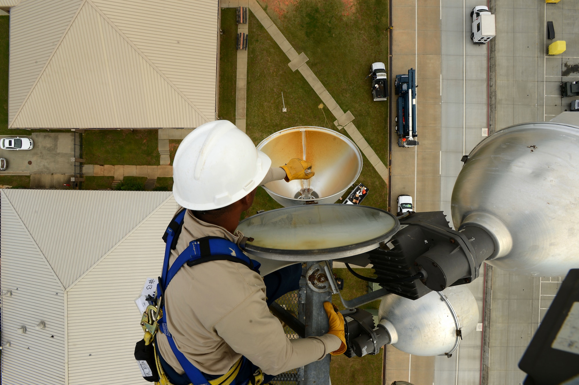 U.S. Air Force Senior Airman Anthony Pierce, 20th Civil Engineer Squadron electrical systems journeyman, installs a light bulb on a ramp light along the flightline at Shaw Air Force Base, S.C., Oct. 16, 2014. Due to the dangers associated with perfoming ramp light maintenance, each of the Airmen wore a safety harness and hard hat. (U.S. Air Force photo by Airman 1st Class Jensen Stidham/Released)
